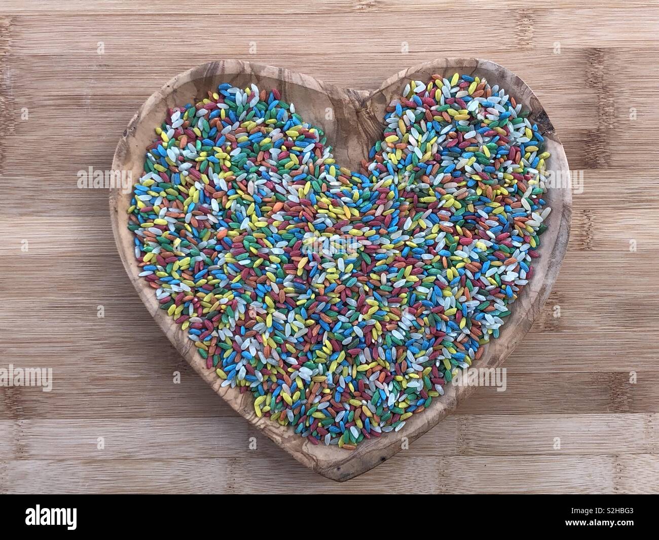 Bunte ehe Reis in eine hölzerne Herz Teller - Smartphone-aufgenommenes Stockfoto