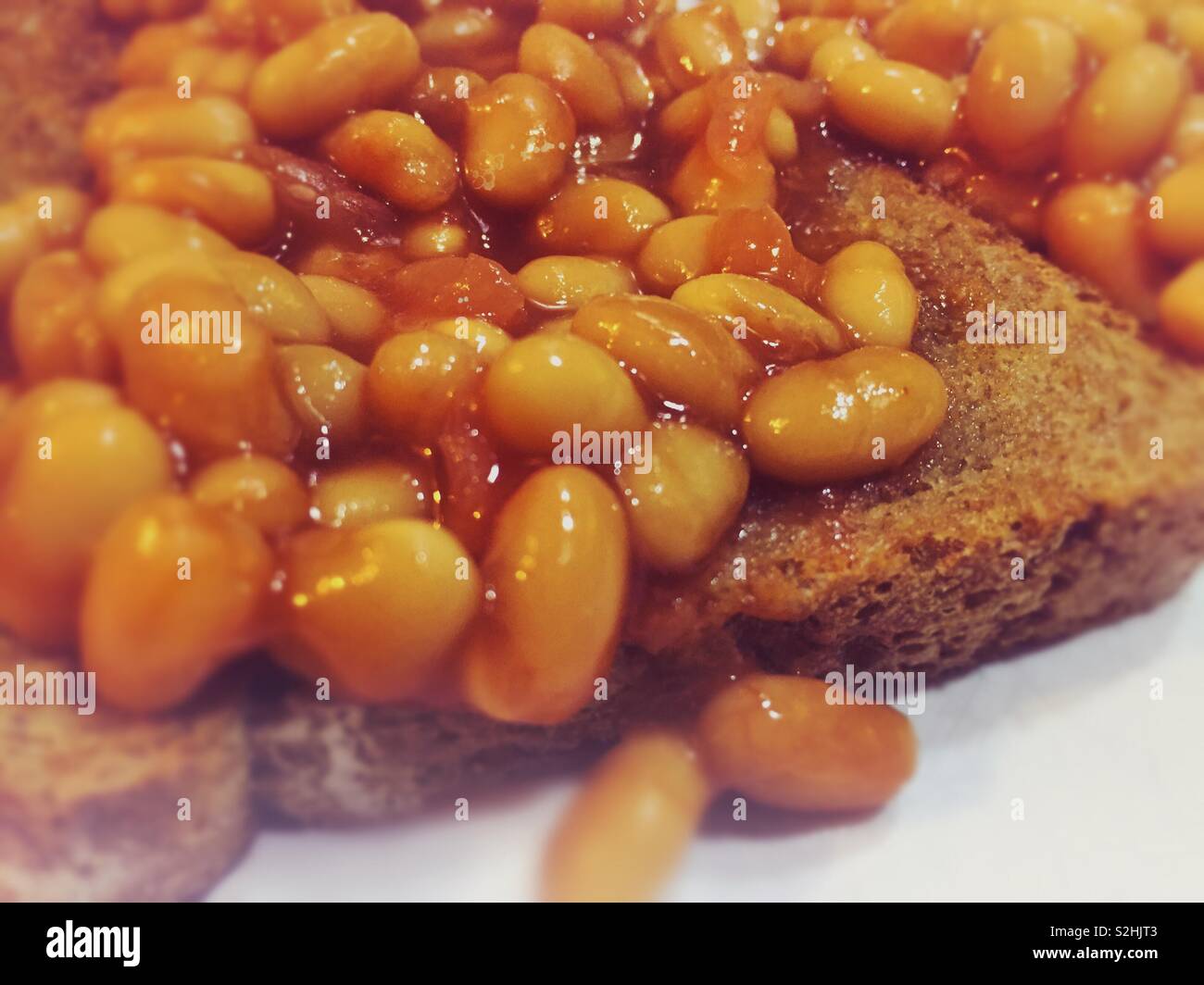 Gebackene Bohnen mit einem leichten Bokeh. Lebendige Farben auf Toast. Frühstück wochentags Idee Inspiration und ideal für Kinder oder diejenigen, die Faser und Protein Stockfoto