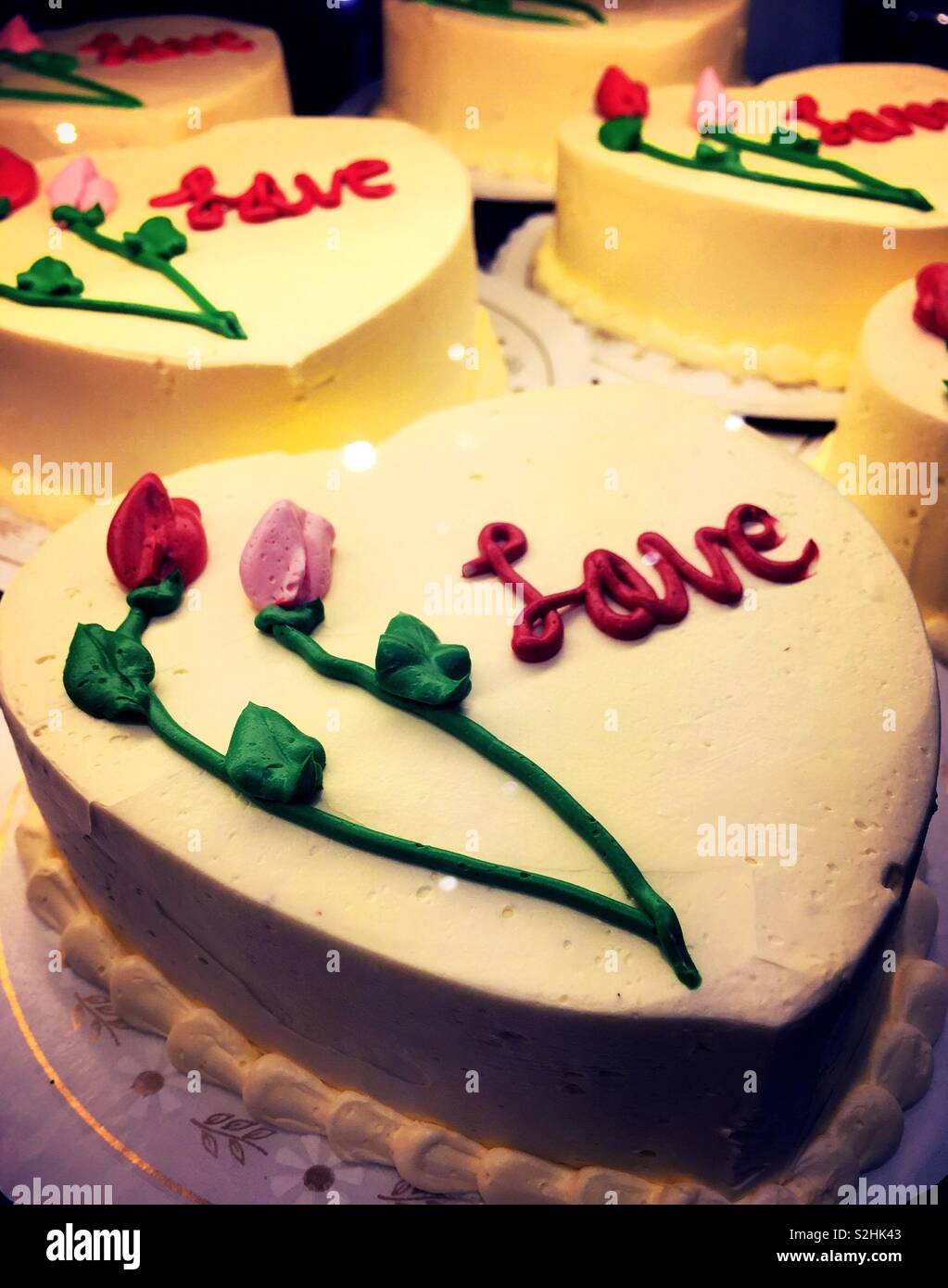Herz geformten Kuchen für den Verkauf in einem Valentinstag Anzeige an einer Bäckerei Stockfoto