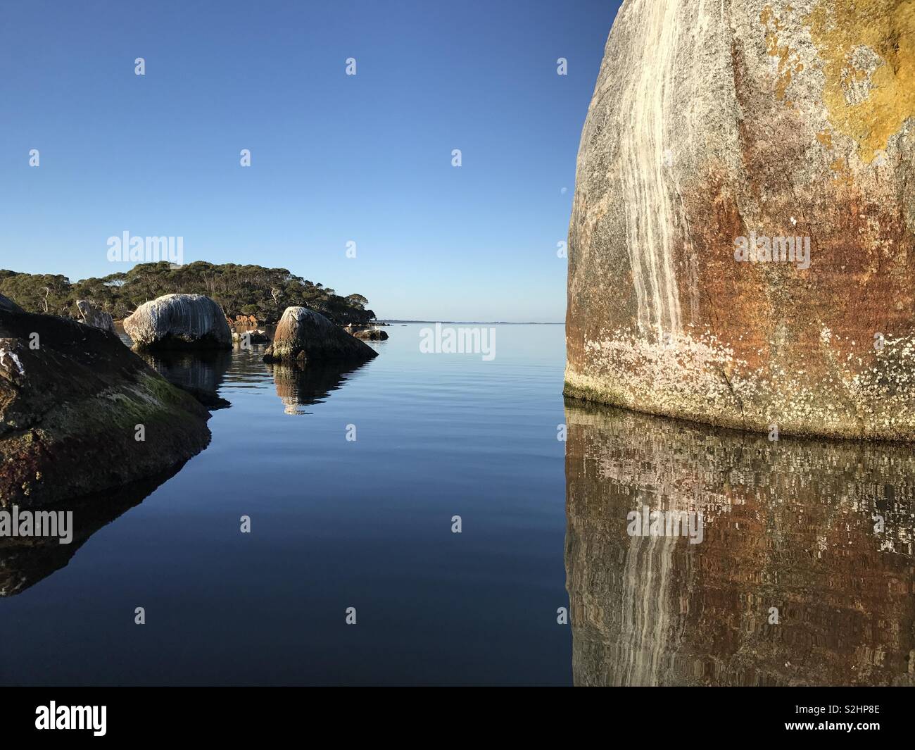 Reflexion eines Boulder im noch ruhigen Wasser Stockfoto