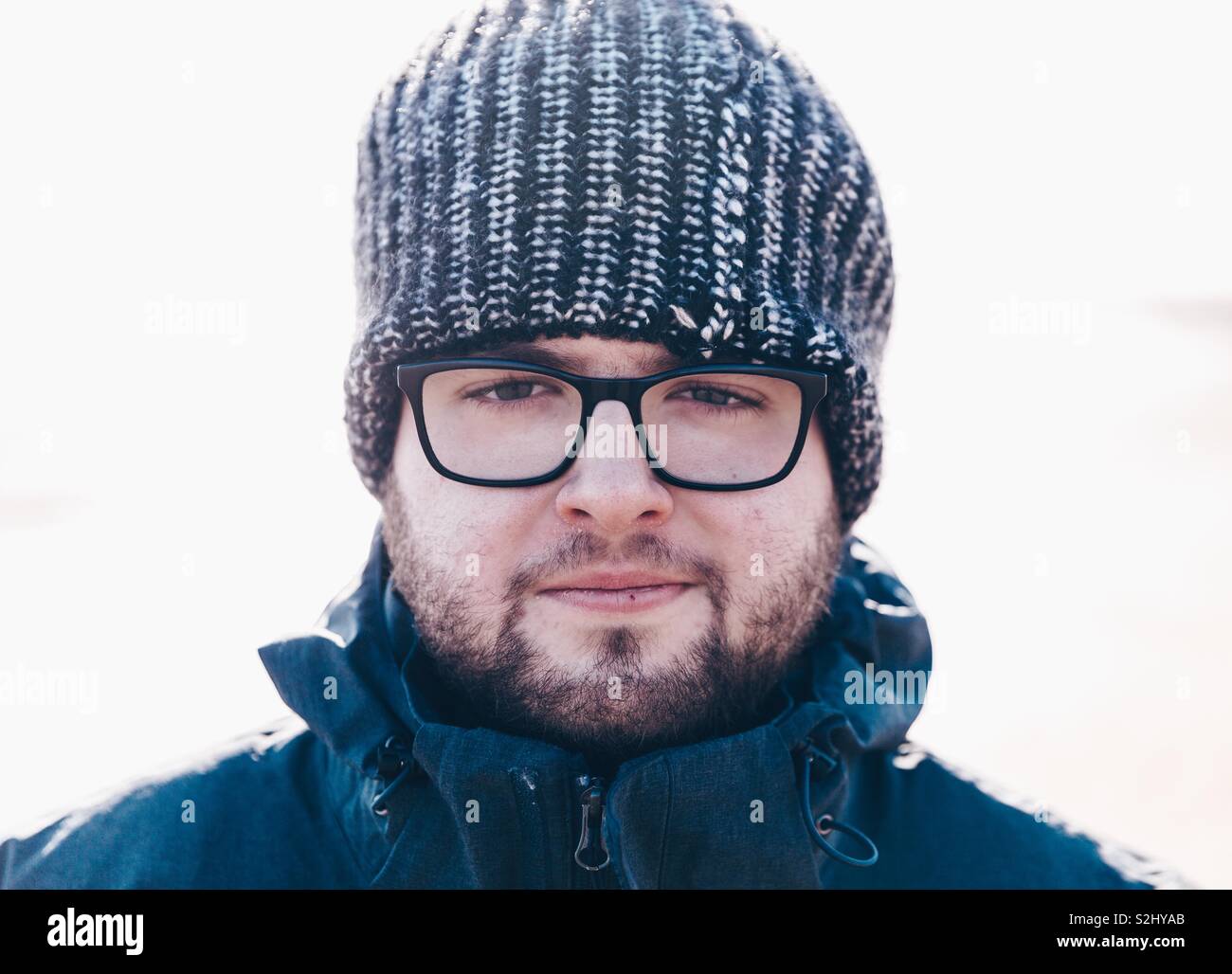 Ein Porträt der jungen männlichen Abenteurer mit Brille und Bart tragen  eine dicke Mütze und warme Winterkleidung während direkt in die Kamera  schaut Stockfotografie - Alamy