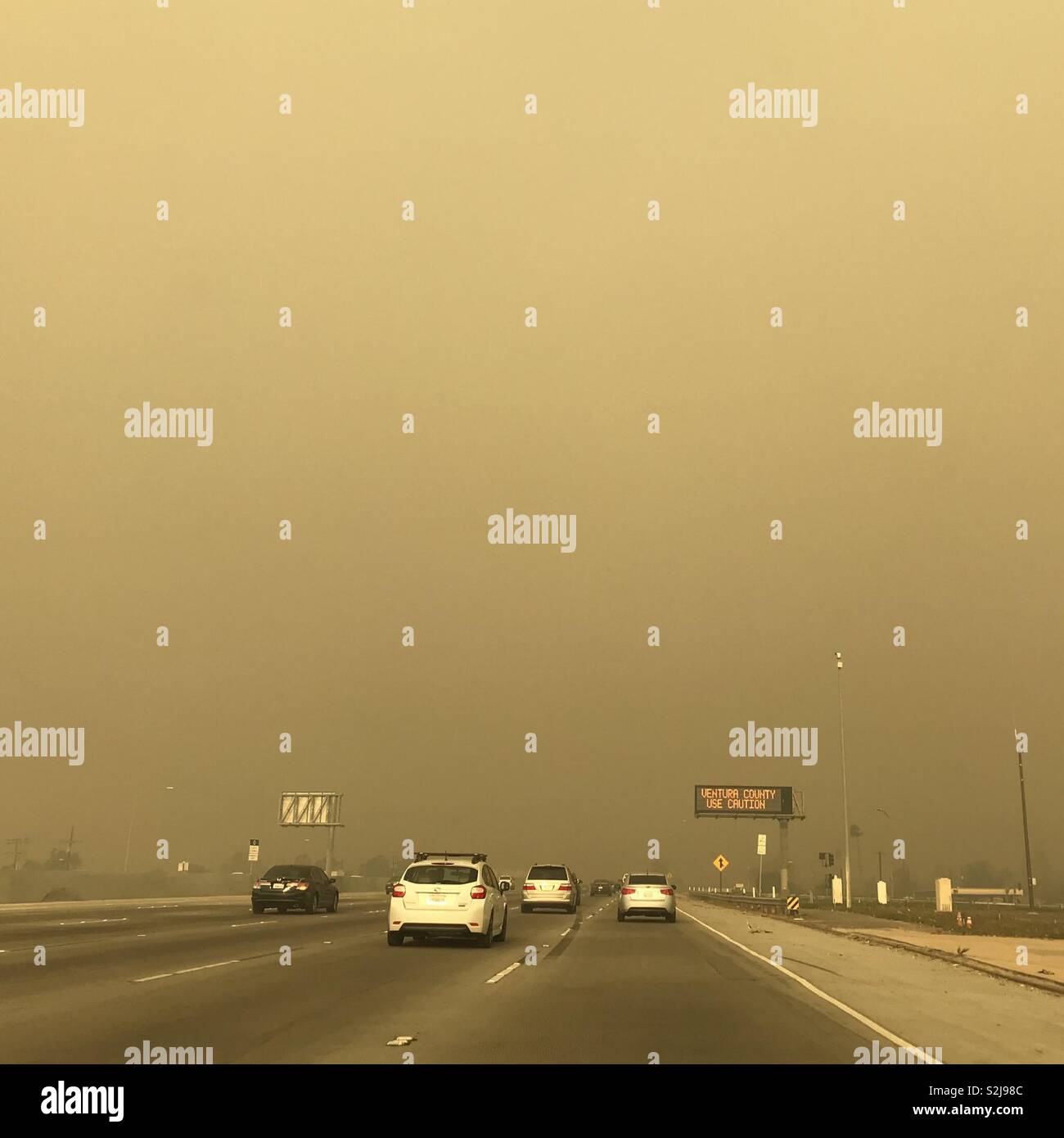 Dicken, braunen Rauch von einem großen wildfire umfasst eine zwischenstaatliche Fahrbahn reduziert die Sichtbarkeit in Kalifornien, USA. Stockfoto