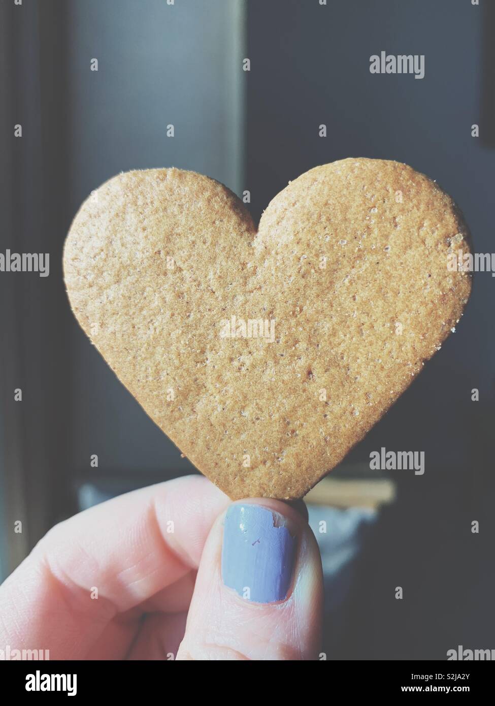 Hand, eine herzförmige Honigkuchen cookie - Smartphone-aufgenommenes Stockfoto