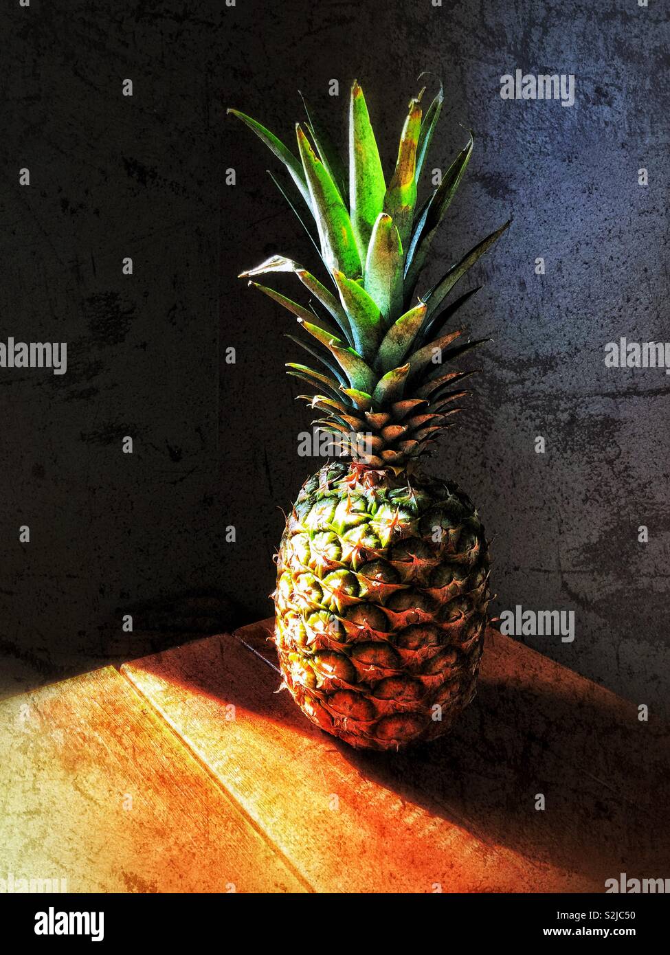 Ananas auf Holztisch mit Sonnenlicht Stockfoto