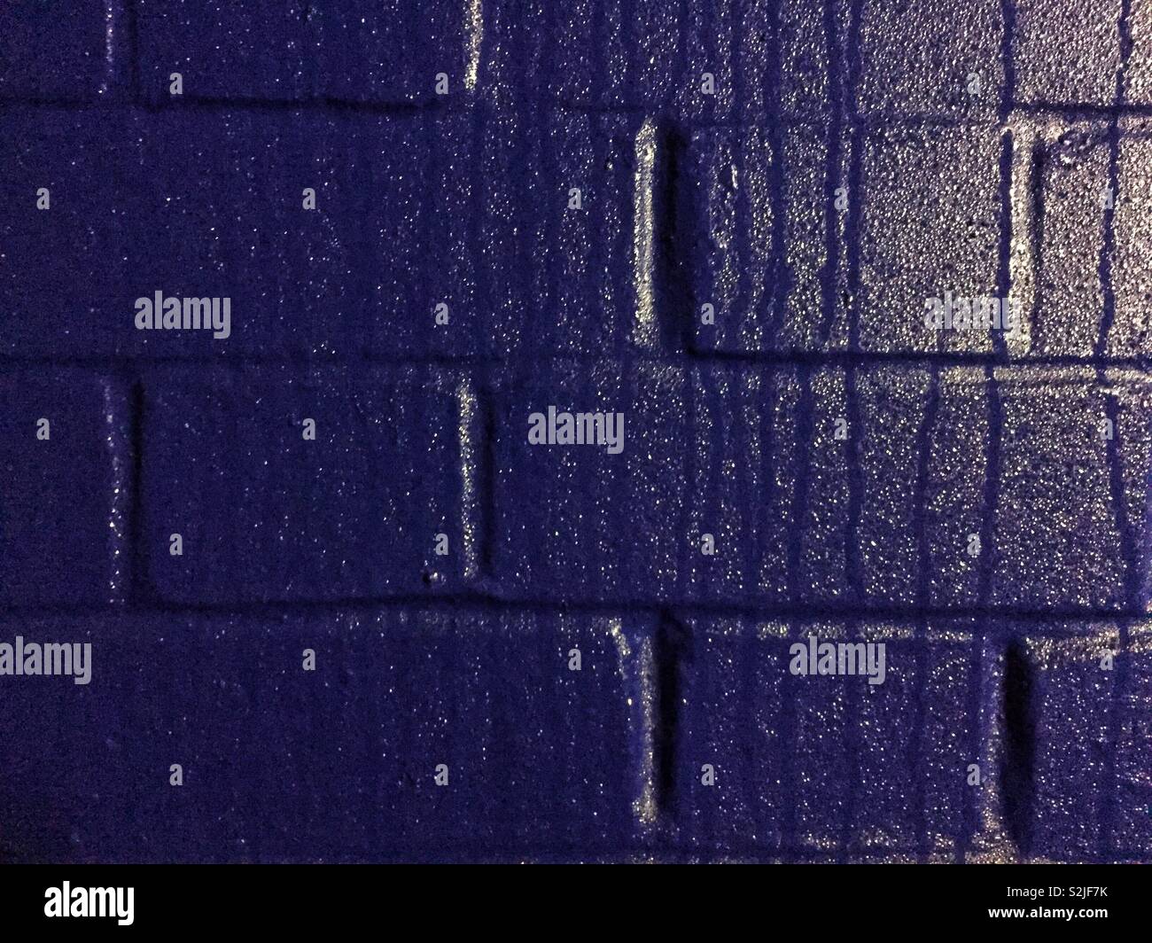 Ein Vollbild, ziegelwand Hintergrund, das tiefe Blau lackiert ist und Kondensation, die Tropf ist die Mauer fallen Stockfoto