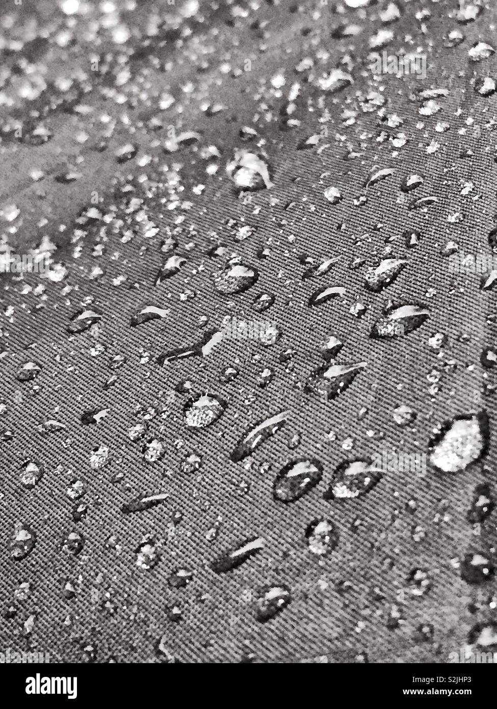 Regentropfen und Regen auf der Leinwand Material von einem Regenschirm. Regentag und Wassertropfen bilden. Unwetterwarnung und schlechte Prognose. Notwendigkeit, trocken zu bleiben. Großbritannien London Manchester Glasgow Birmingham Stockfoto