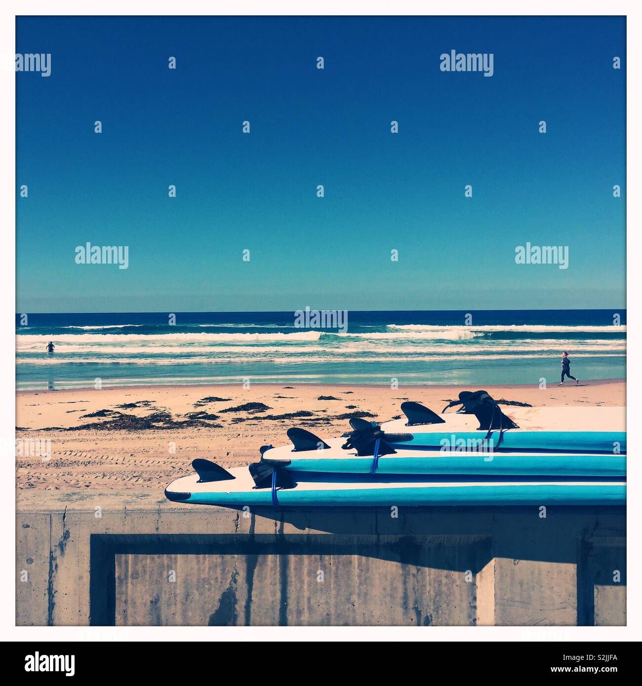 Drei blaue und weiße Surfbretter sind in eine Wand an einem San Diego Strand gestapelt. Stockfoto