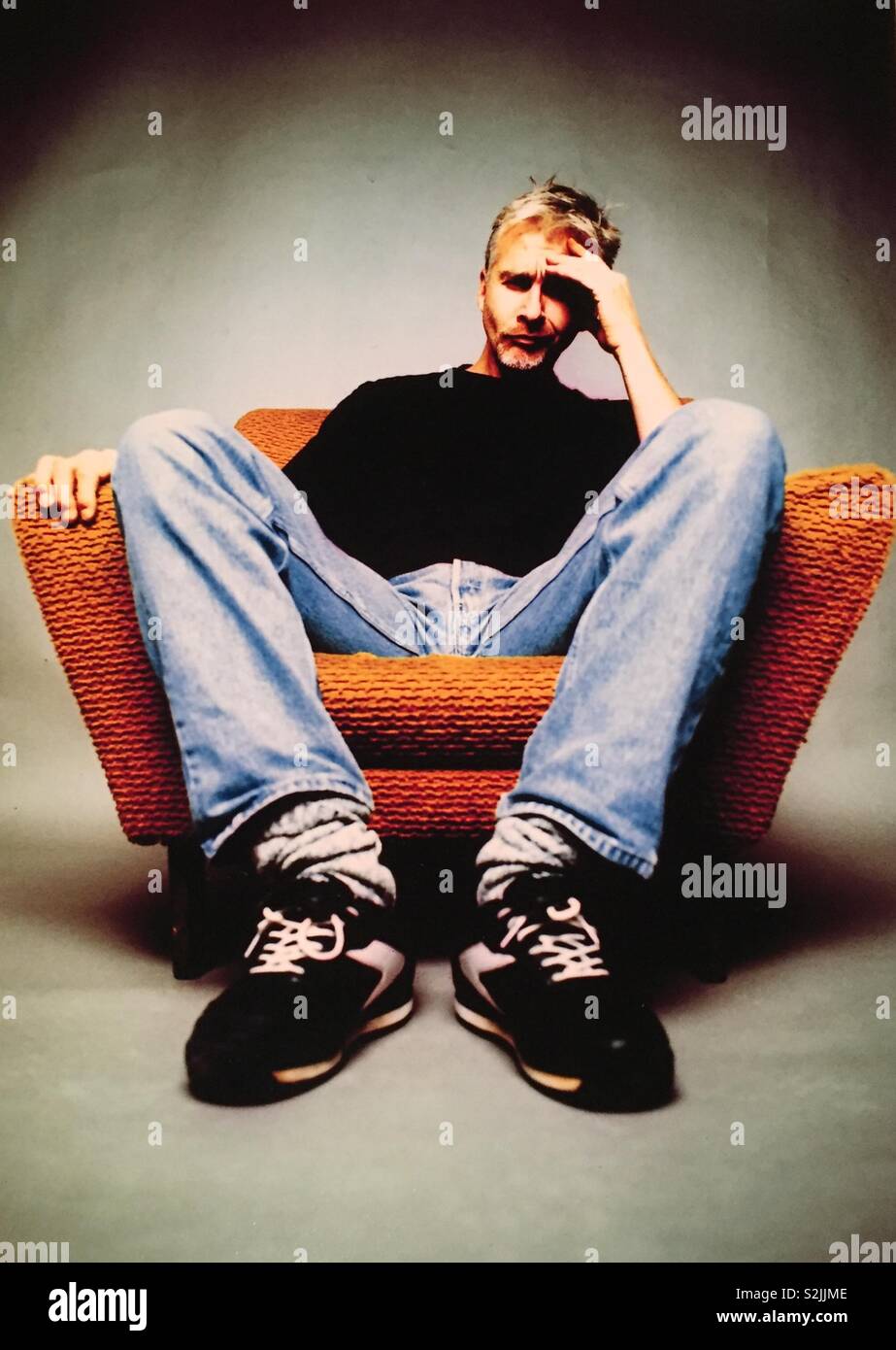 Mann sitzt im Stuhl mit Hand auf den Kopf - Smartphone-aufgenommenes Stockfoto