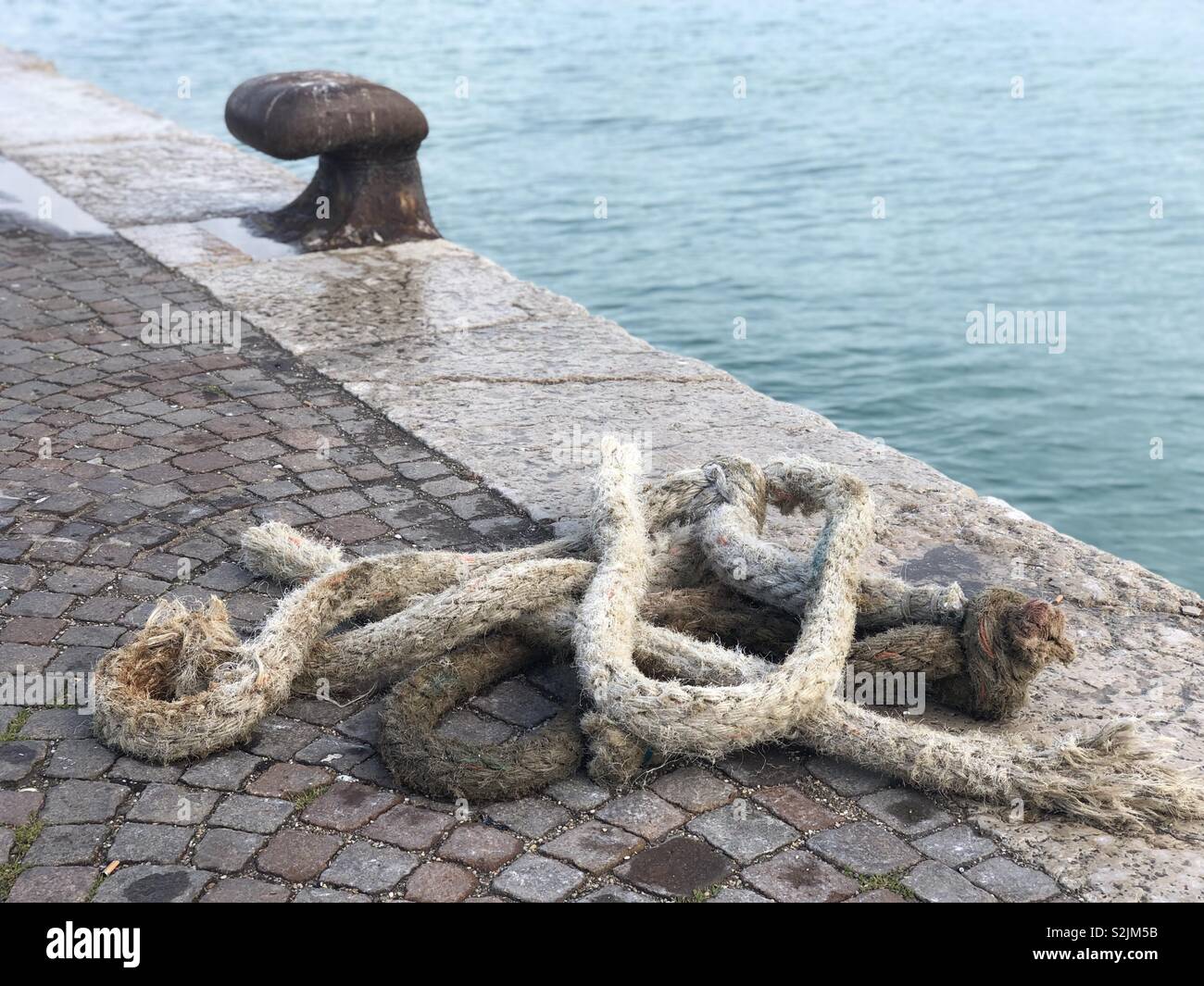 Alte Metall rostig Liegeplatz Poller mit einem festmacher Seil - Smartphone-aufgenommenes Stockfoto