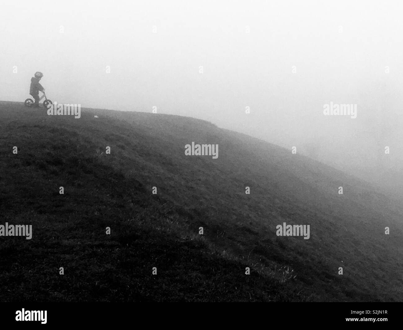 Junge Kind auf seinem Fahrrad auf Hill Top gegen misty Hügel Stockfoto