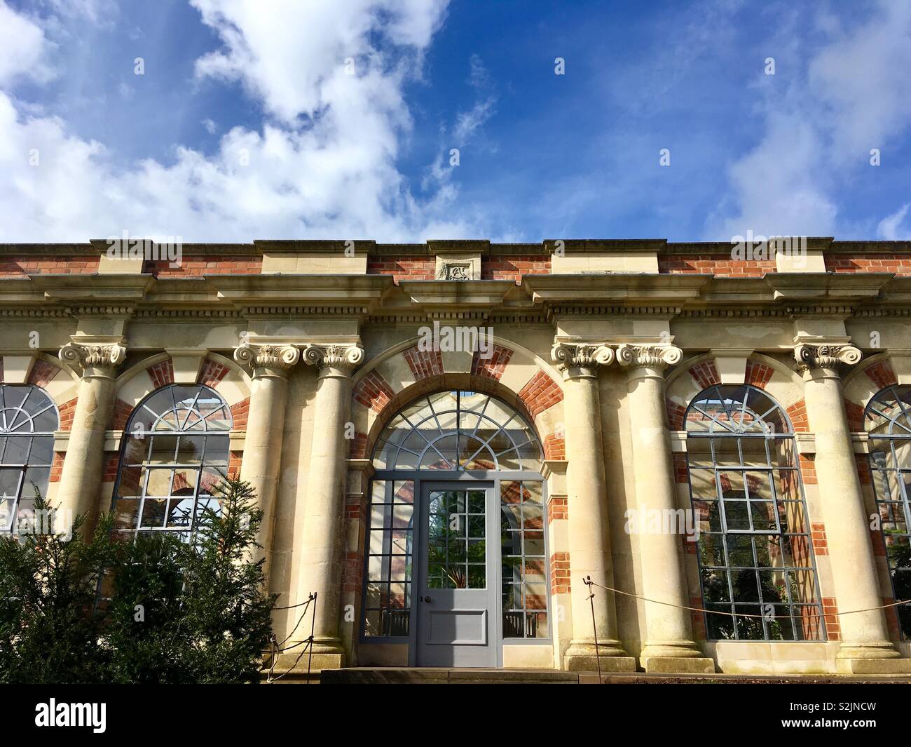 Eine teure, klassische Orangerie unter einem blauen Himmel mit einigen weissen Wolken - Smartphone-aufgenommenes Stockfoto