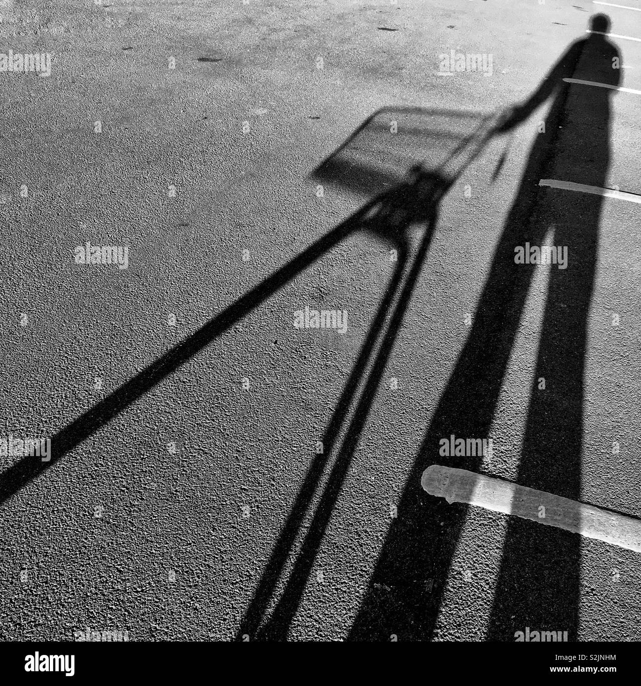 Ein Schwarz/Weiß-Aufnahme der lange Schatten eines Mannes mit Supermarkt Trolley. Platz kopieren Stockfoto