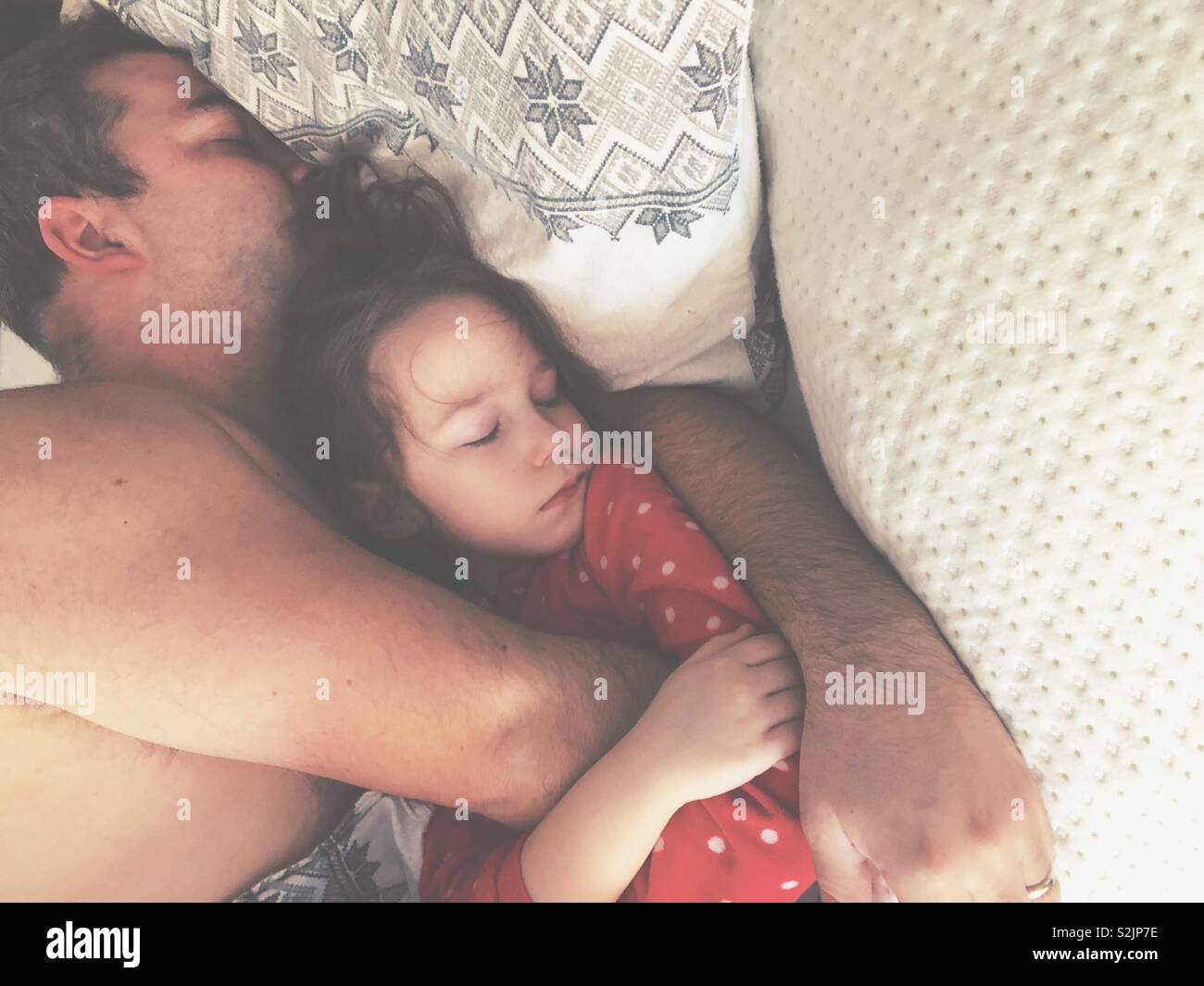 Junge Tochter schlafen Kuscheln mit Vater im Bett der Eltern Stockfoto