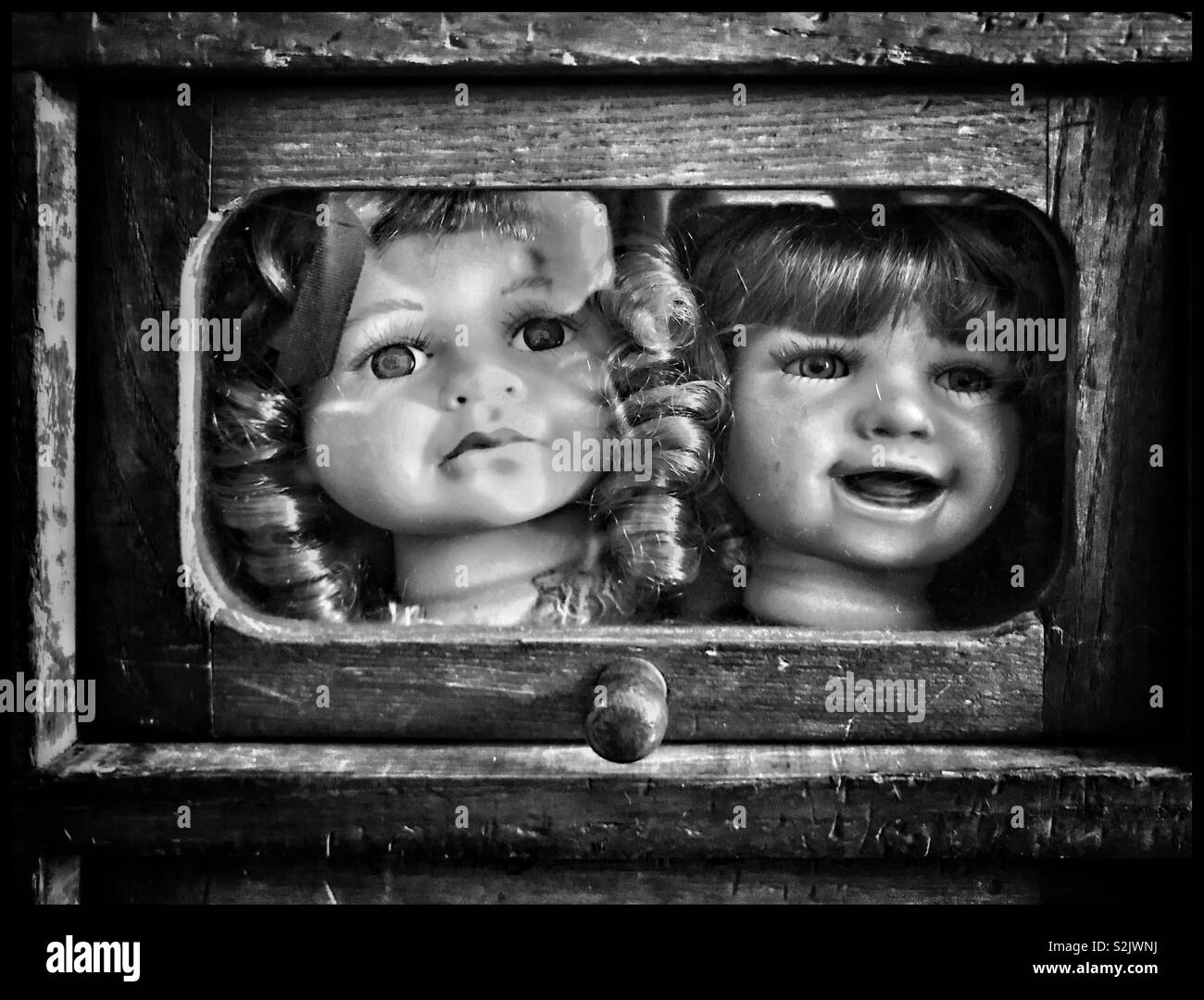 Zwei Puppen Köpfe in einem Holz- Container eingeschlossen. Wo ist der Rest von Ihrem Körper? Komisch, lustig oder einfach nur grotesk? Ein Bild mit einer Nachricht? Foto - © COLIN HOSKINS. - Smartphone-aufgenommenes Stockfoto