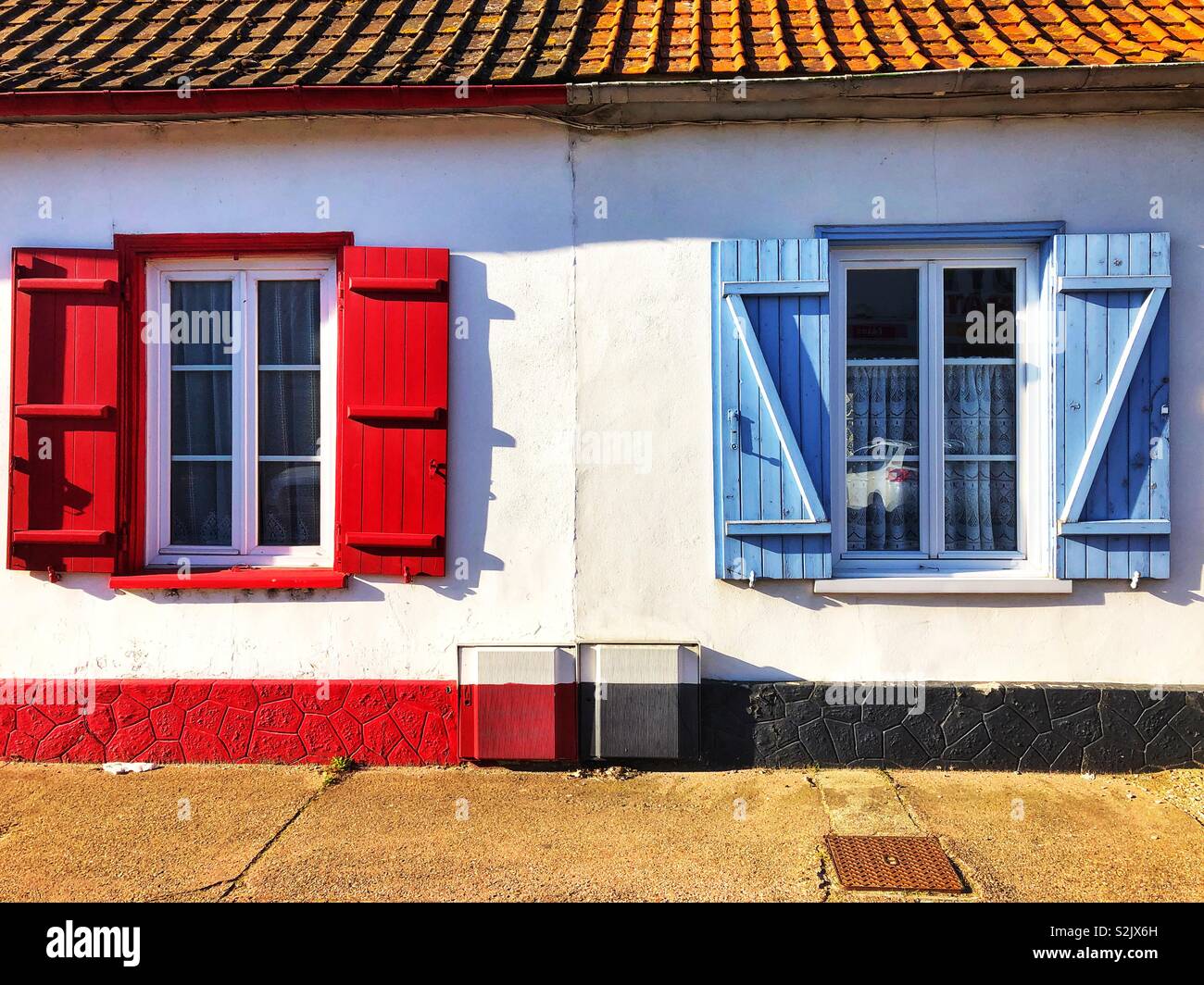 Zwei Fenster mit roten und blauen Fensterläden, Frankreich. Stockfoto