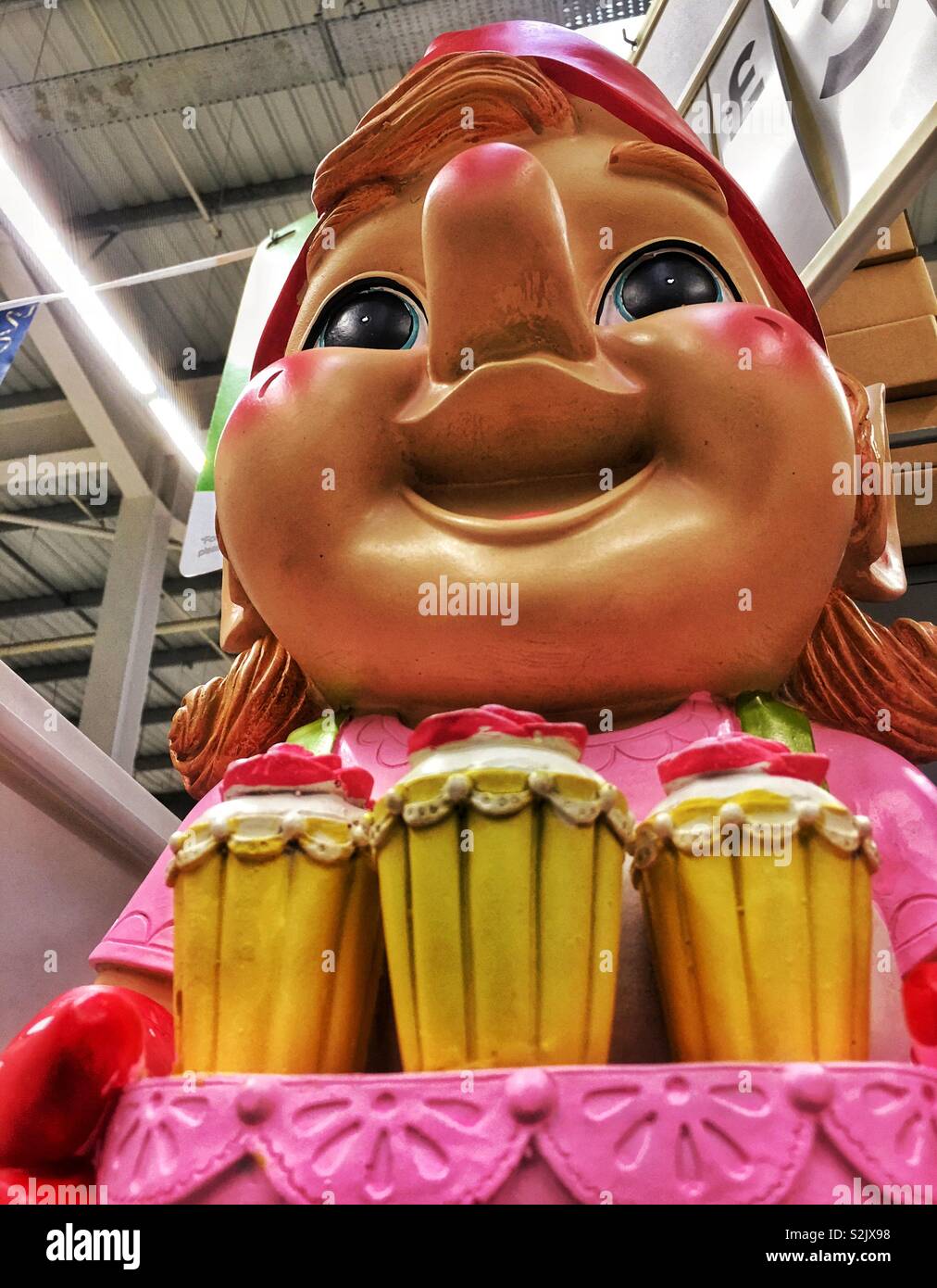 Suchen bis zu einem großen bunten Garten gnome Durchführung Eiscremeeiscremebechern in einem Supermarkt. Stockfoto