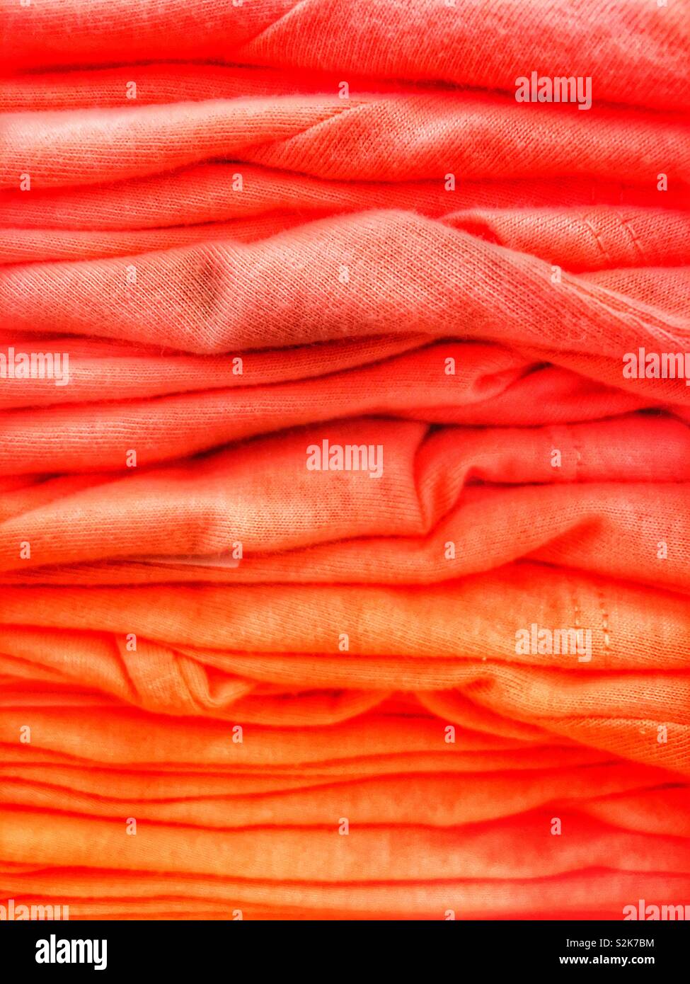 Große Stapel von Coral farbige Pullover. - Smartphone-aufgenommenes Stockfoto