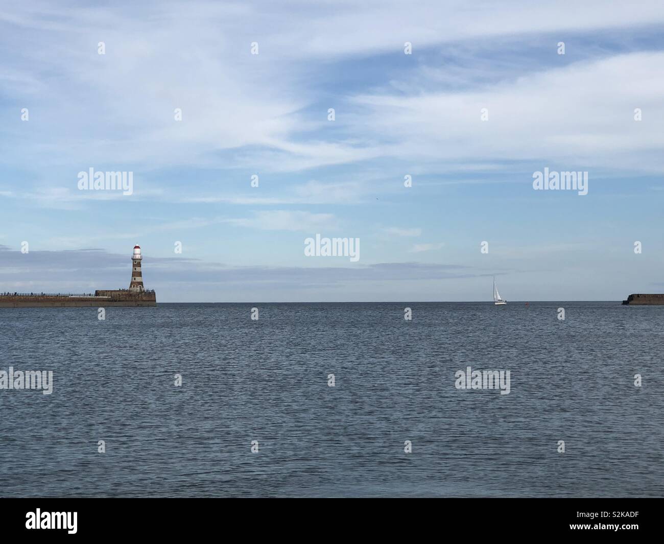 Auf der Suche von Roker Strand zu sehen und erfassen ein Leuchtturm und Boot. Stockfoto