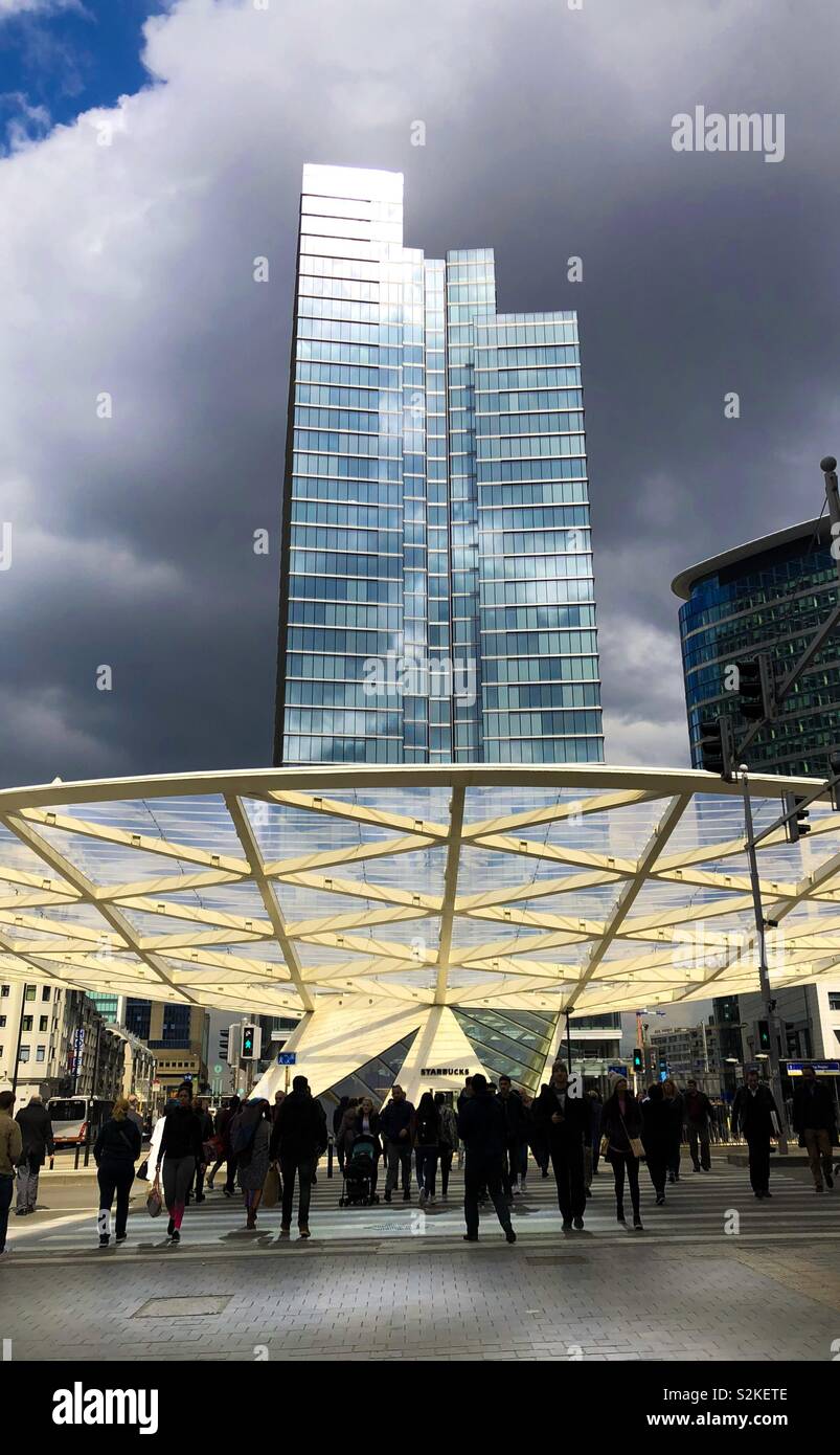 Büro gebäude Turm gegen einen dunklen stürmischen Himmel im Hintergrund und Silhouetten von Menschen in den Vordergrund. - Smartphone-aufgenommenes Stockfoto