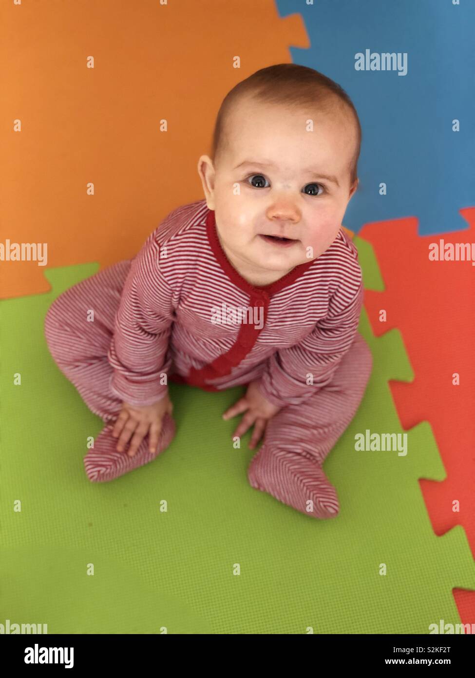Baby auf farbigem Schaum Spielteppich Quadrate lächelnd Stockfoto