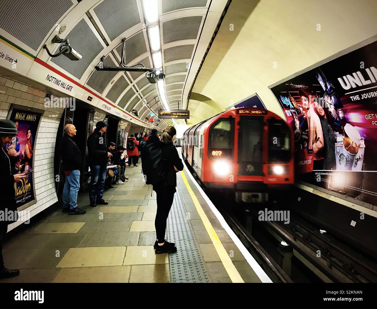 Eine Frau wartet auf der Plattform als ein Zug in Notting Hill Gate U-Bahnhof ankommt. - Smartphone-aufgenommenes Stockfoto