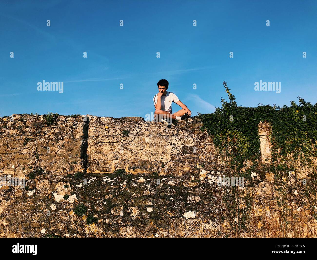 Junge sitzt auf einer Wand Stockfoto