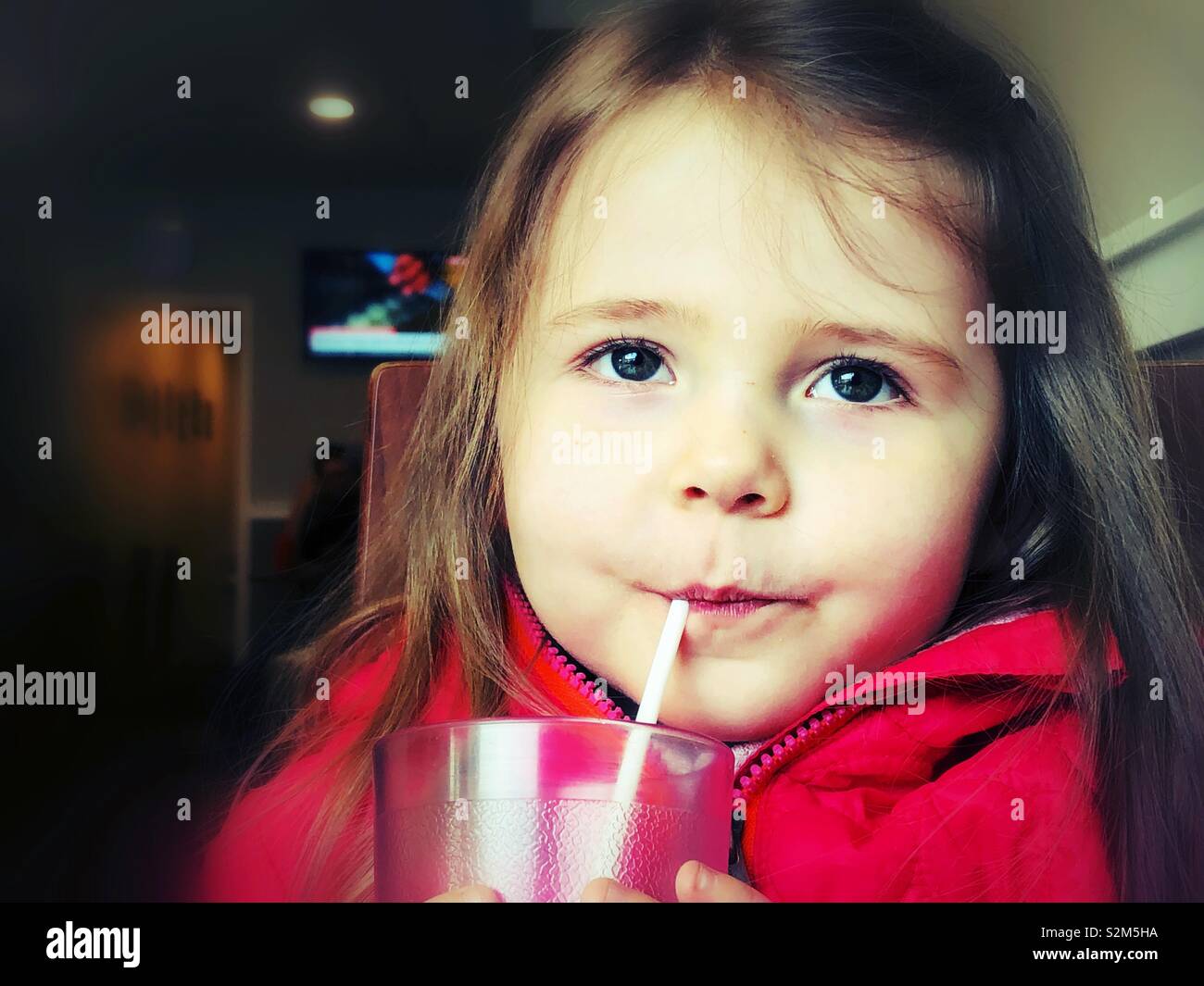 Junge Mädchen Saft trinken mit einem Kunststoff Stroh Stockfoto