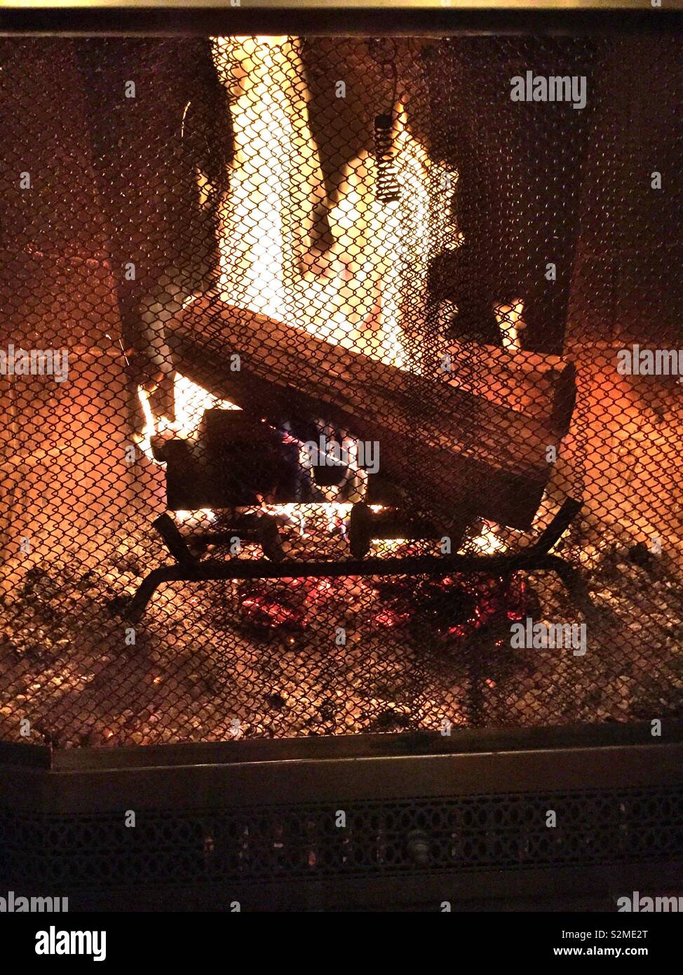 Ein knisterndes Feuer, wie durch den Bildschirm zu einem Wohngebiet Kamin gesehen, USA Stockfoto