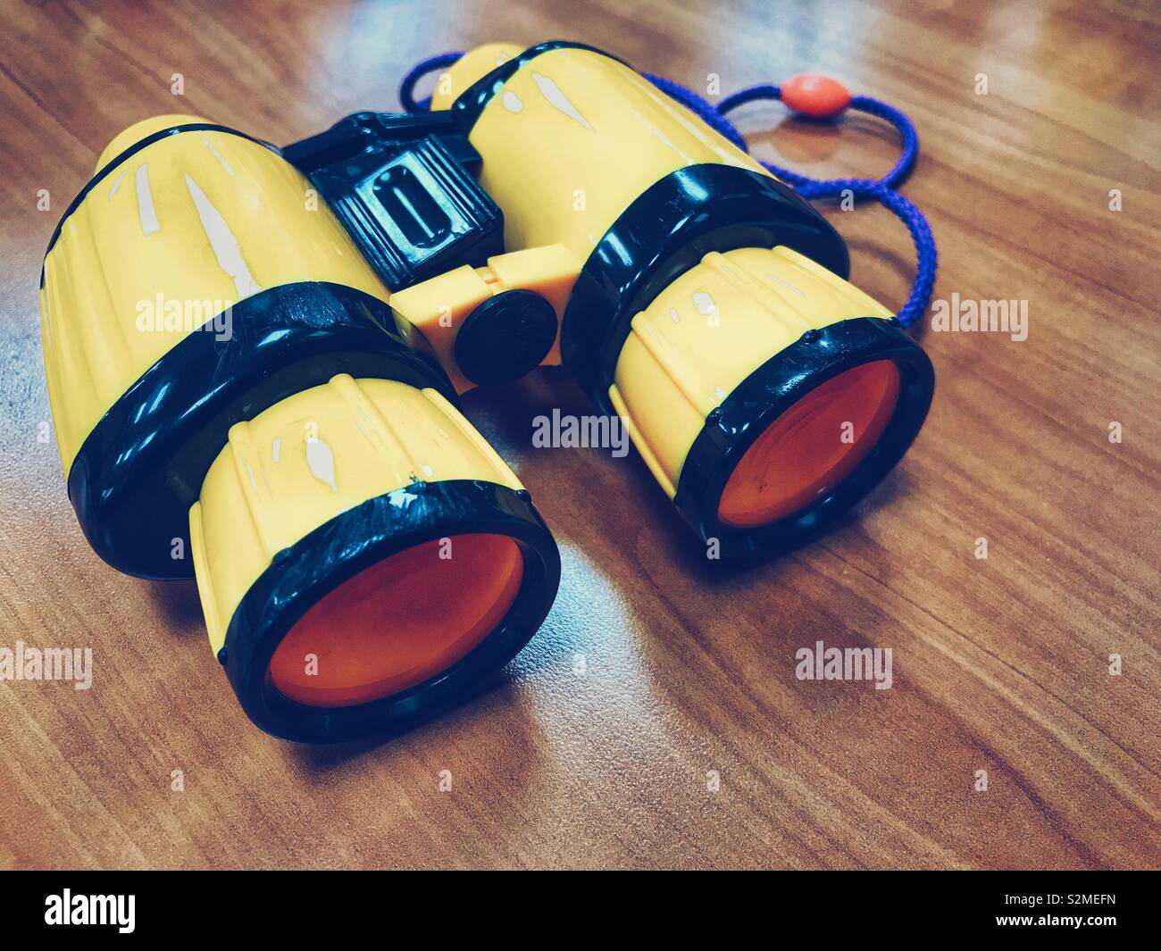 Gelb Kunststoff Spielzeug Fernglas Spielzeug des Kindes auf einem Holztisch. Stockfoto