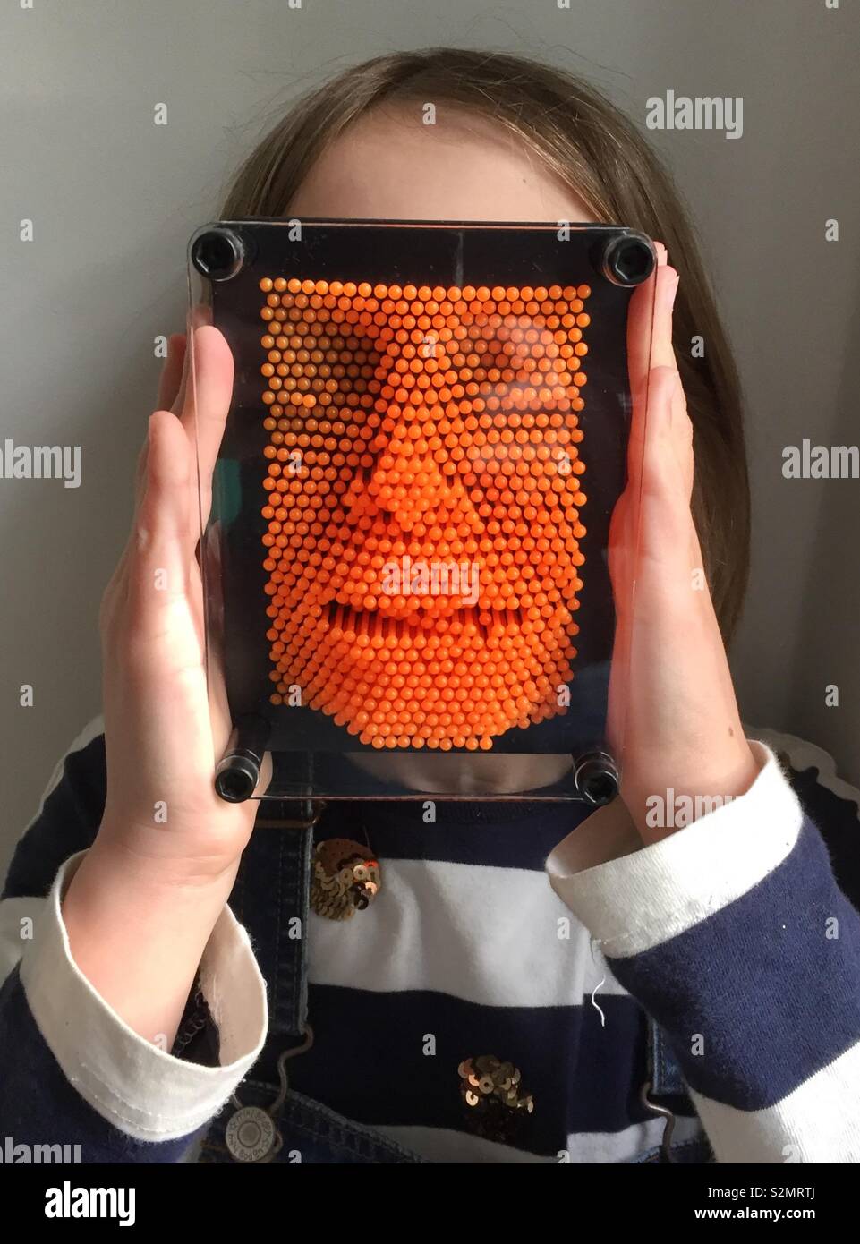 Weibliches Kind mit einer orange pinart in ihrem Gesicht - Smartphone-aufgenommenes Stockfoto