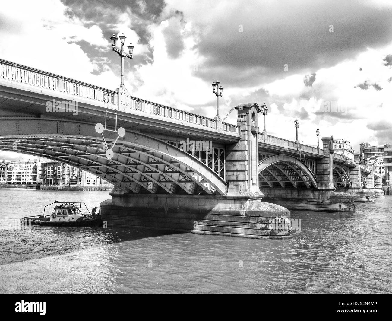 Ein Boot vor Anker unter den Bögen der Southwark Bridge über die Themse in London, England, mit Blick auf die North Bank. Stockfoto