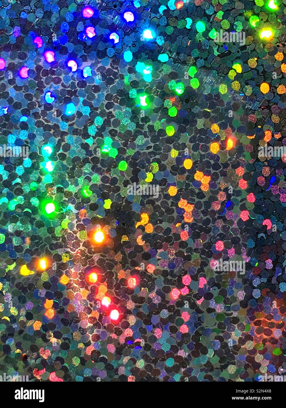 Hell Blau, Gelb, Orange und Grün bunte Holografische, abstrakte und prismatische Anordnung von kleinen winzigen Pailletten in das Licht reflektieren. Stockfoto