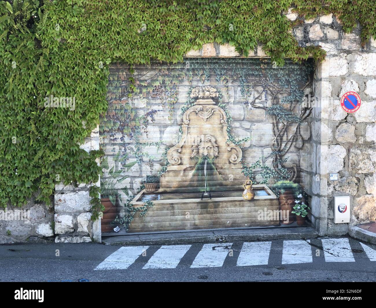 Eine außergewöhnliche Trompe l'oeil/optische Täuschung verwendet ein garagentor als Brunnen an der Riviera, Frankreich zu verbergen. - Smartphone-aufgenommenes Stockfoto