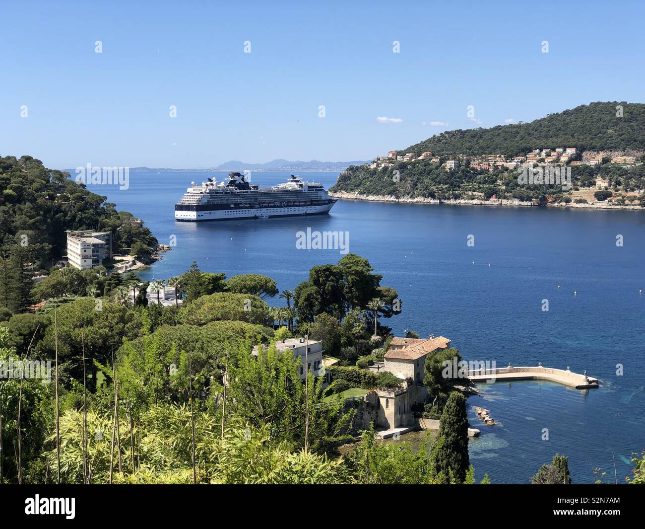 Eine dramatische und wunderschönen Küsten Einlass an der Riviera gesehen von der Villa Ephrussi auf Cap Ferrat in Richtung Berg Boron und Ville Franche mit einem exotischen Villen und einem Kreuzfahrtschiff Stockfoto