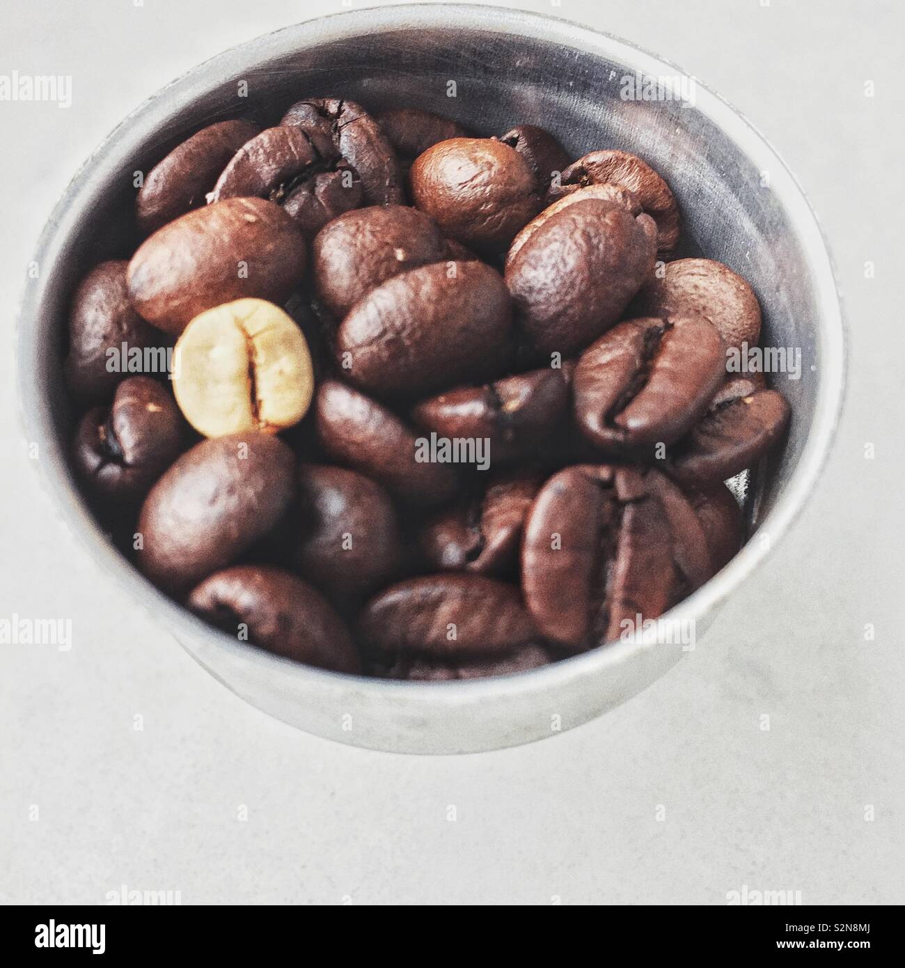 Unter geröstete Kaffeebohne zusammen mit gerösteten Bohnen. - Smartphone-aufgenommenes Stockfoto