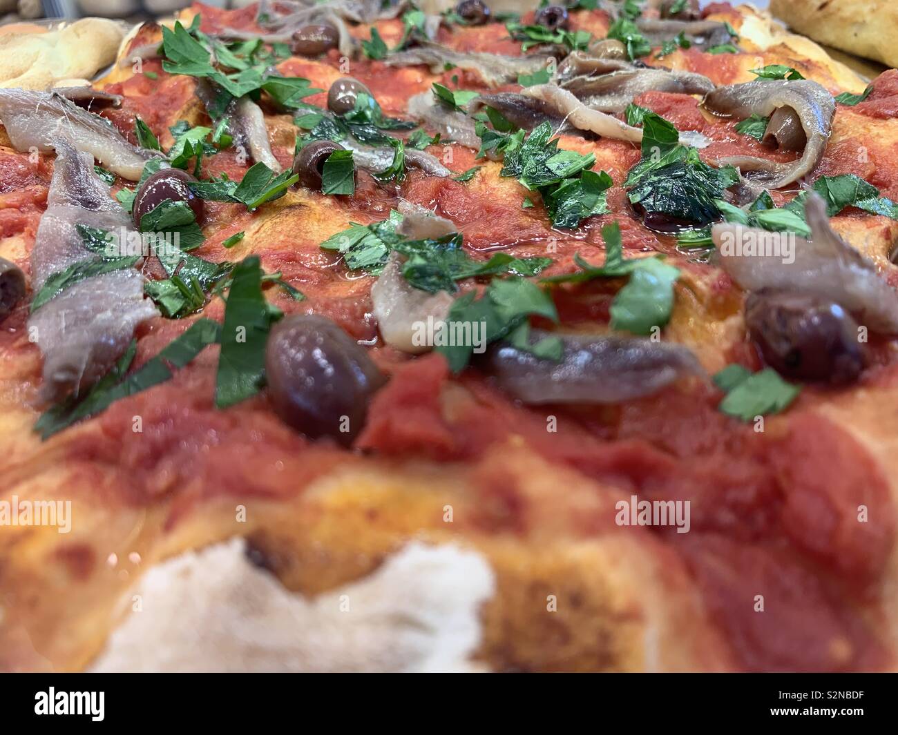 Detail Ansicht über eine rote Pizza mit Oliven und Sardellen Stockfoto