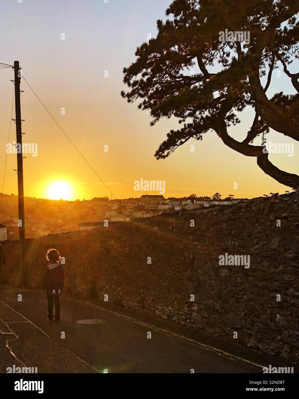 Einsame Junge auf der Straße bei Sonnenuntergang, Brixham, Devon, Großbritannien. Stockfoto