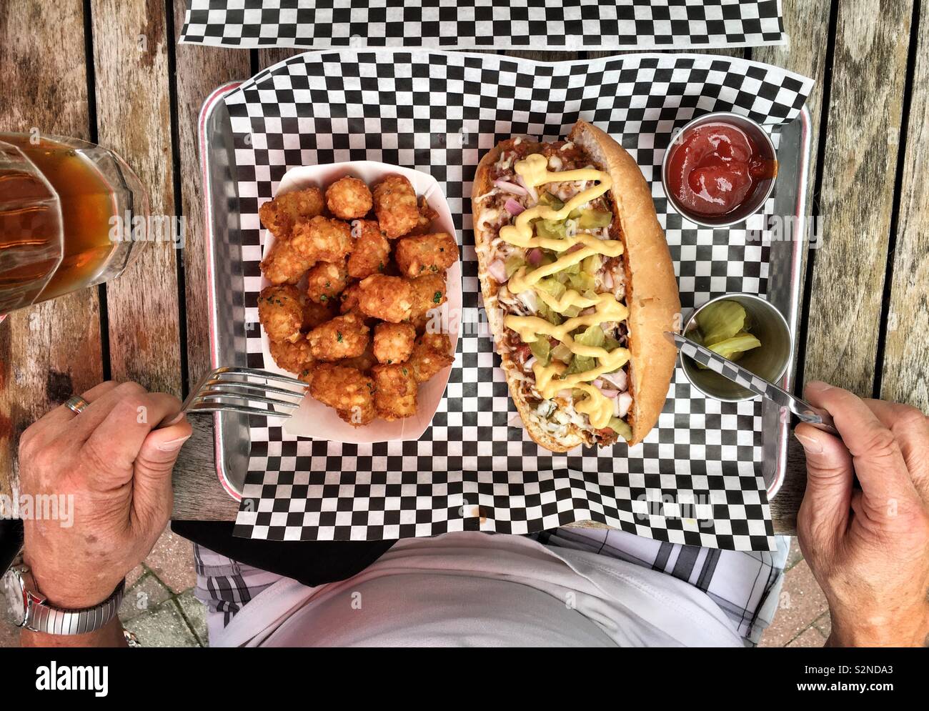 Eine Person mit einer Mahlzeit. Chili hotdog und Tater Tots. Stockfoto