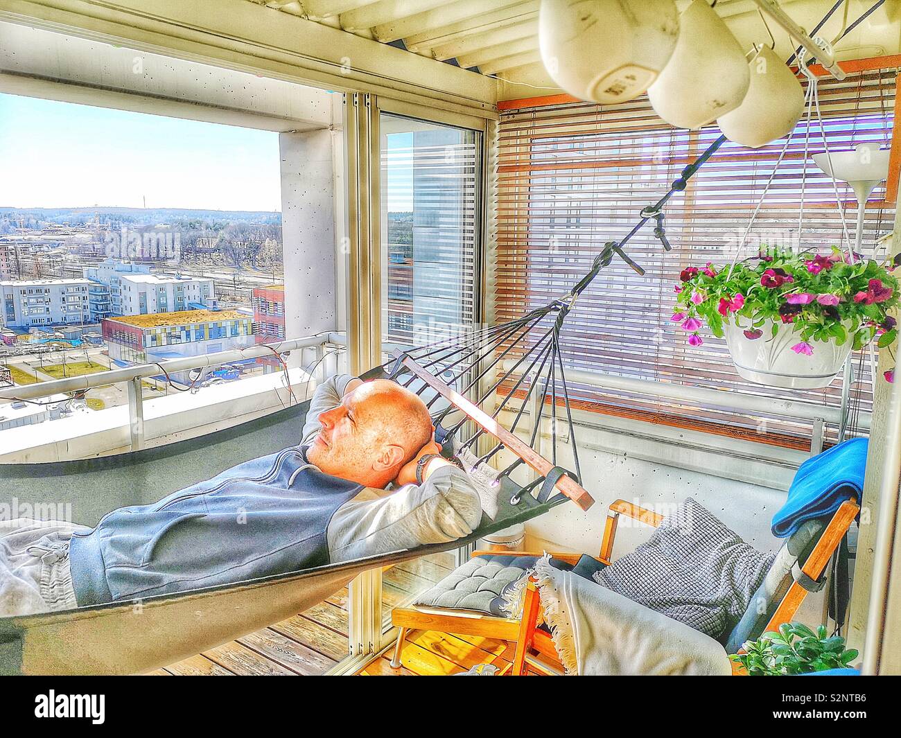 Stattliche Mitte erwachsenen Mann in der Hängematte auf high rise apartment Terrasse, Schweden, Skandinavien Stockfoto