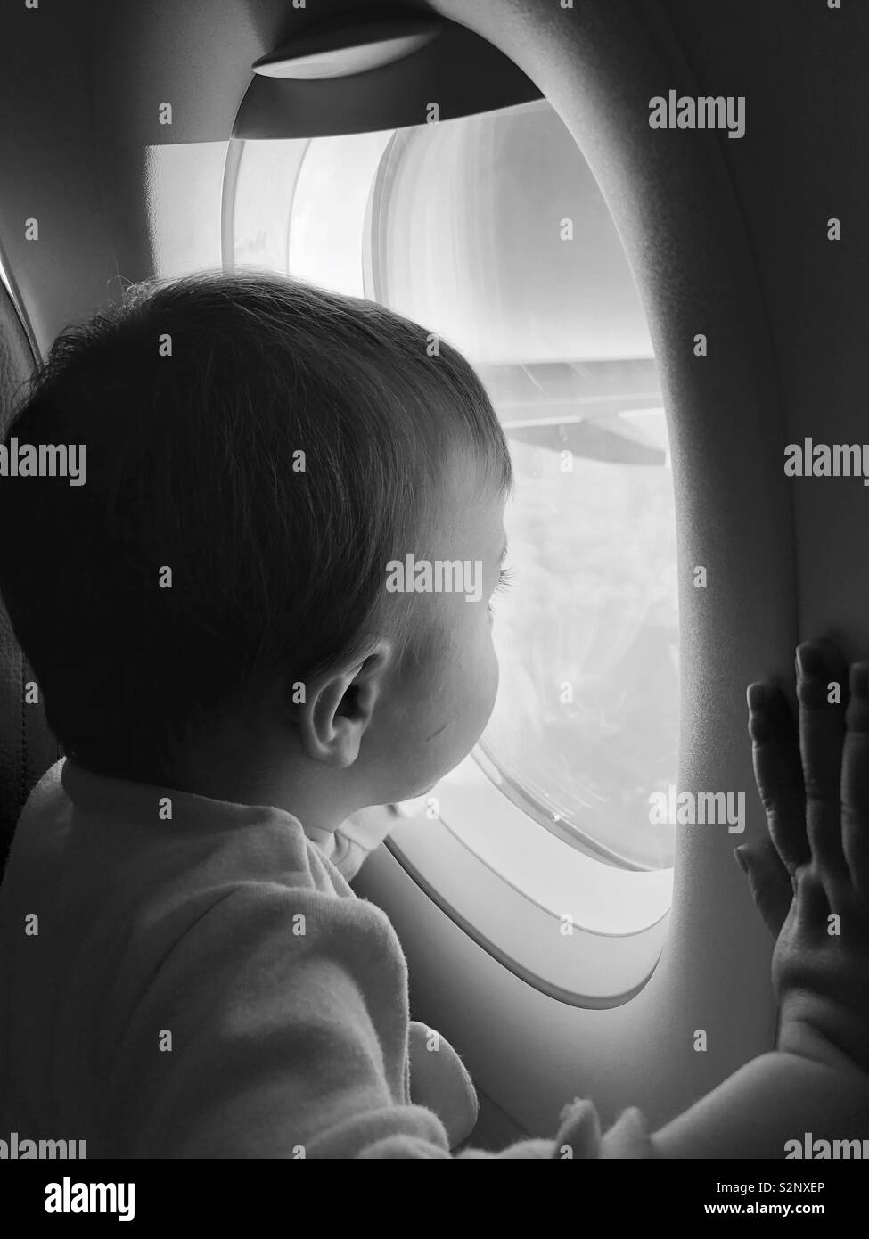 Foto von Neugierig Baby Blick aus dem Flugzeug Fenster Schwarz und Weiß Stockfoto