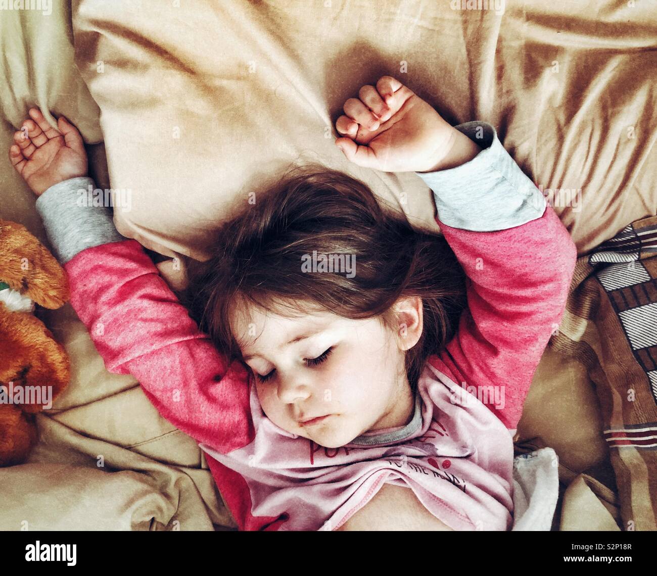 Junge Mädchen schlafen mit Arme Stockfoto