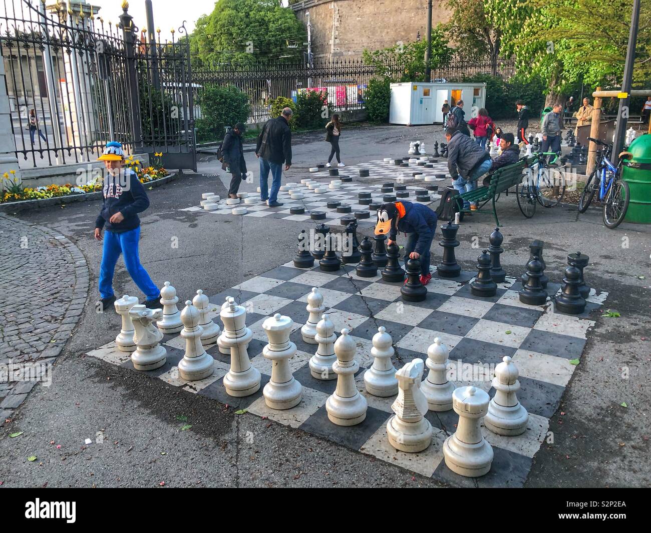 Zwei Jungen spielen Schach mit großen Stücken und großen Schachbrett auf dem Boden von Bastionen Park Genf Schweiz gezeichnet - Smartphone-aufgenommenes Stockfoto
