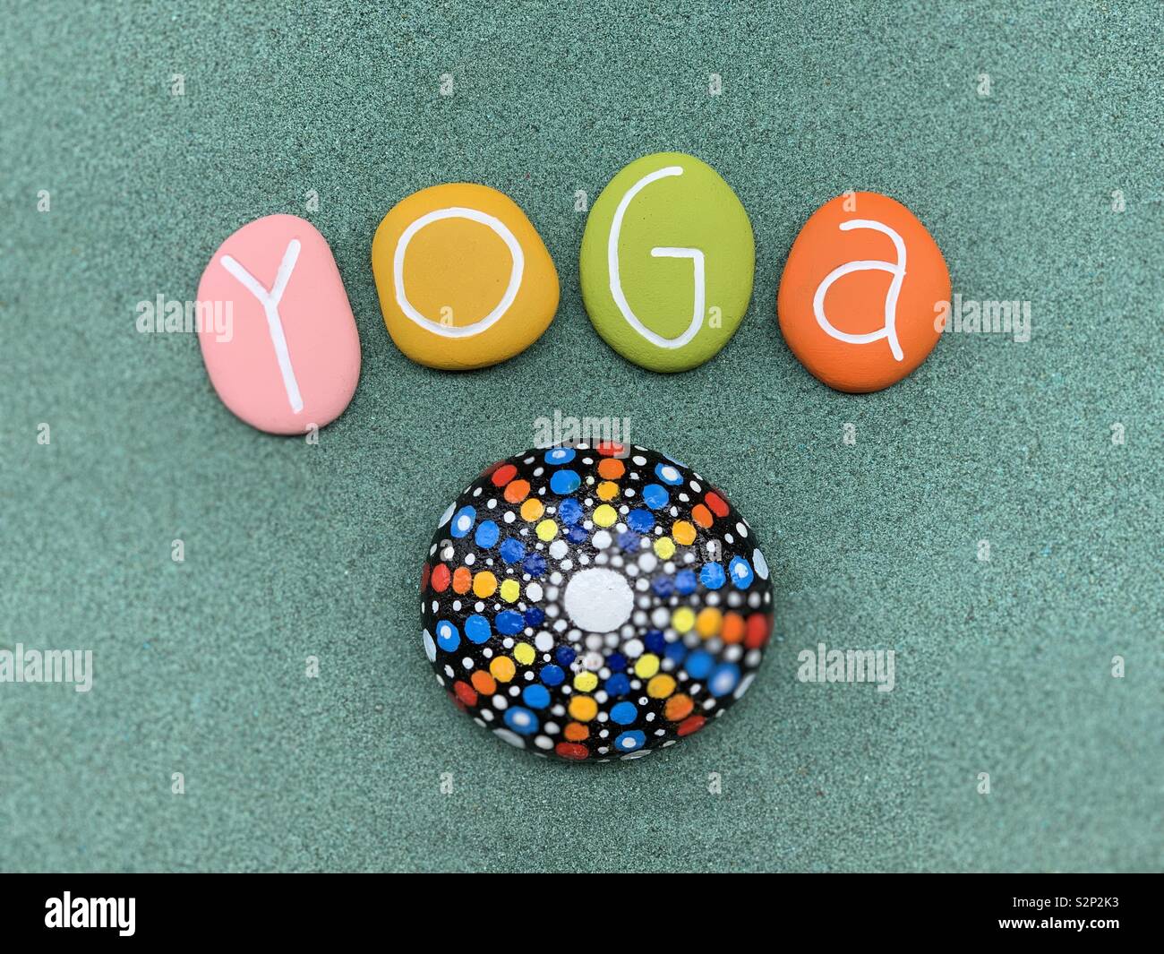 Yoga Text mit bunten Steine mit einem Mandala auf einem Stein gemalt - Smartphone-aufgenommenes Stockfoto