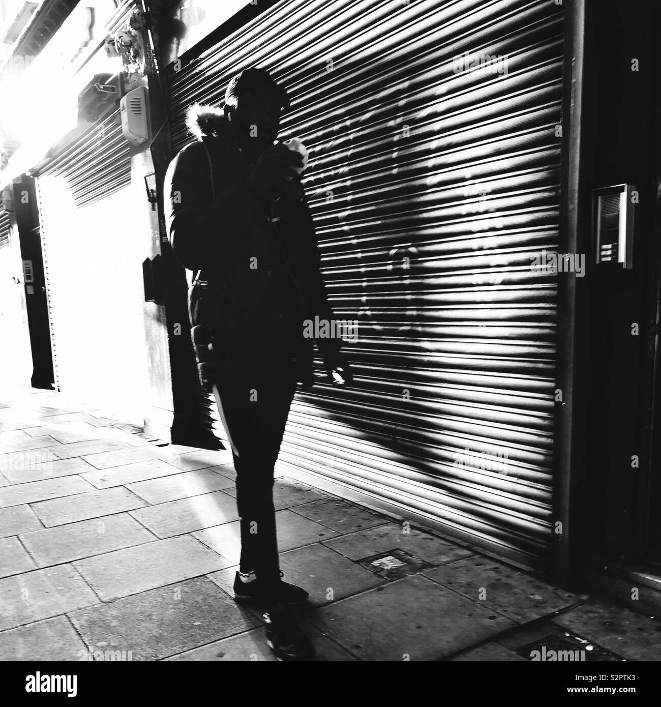 Silhouetted Bild eines Mannes gegen die Hintergrundbeleuchtung shop Fensterläden - Smartphone-aufgenommenes Stockfoto