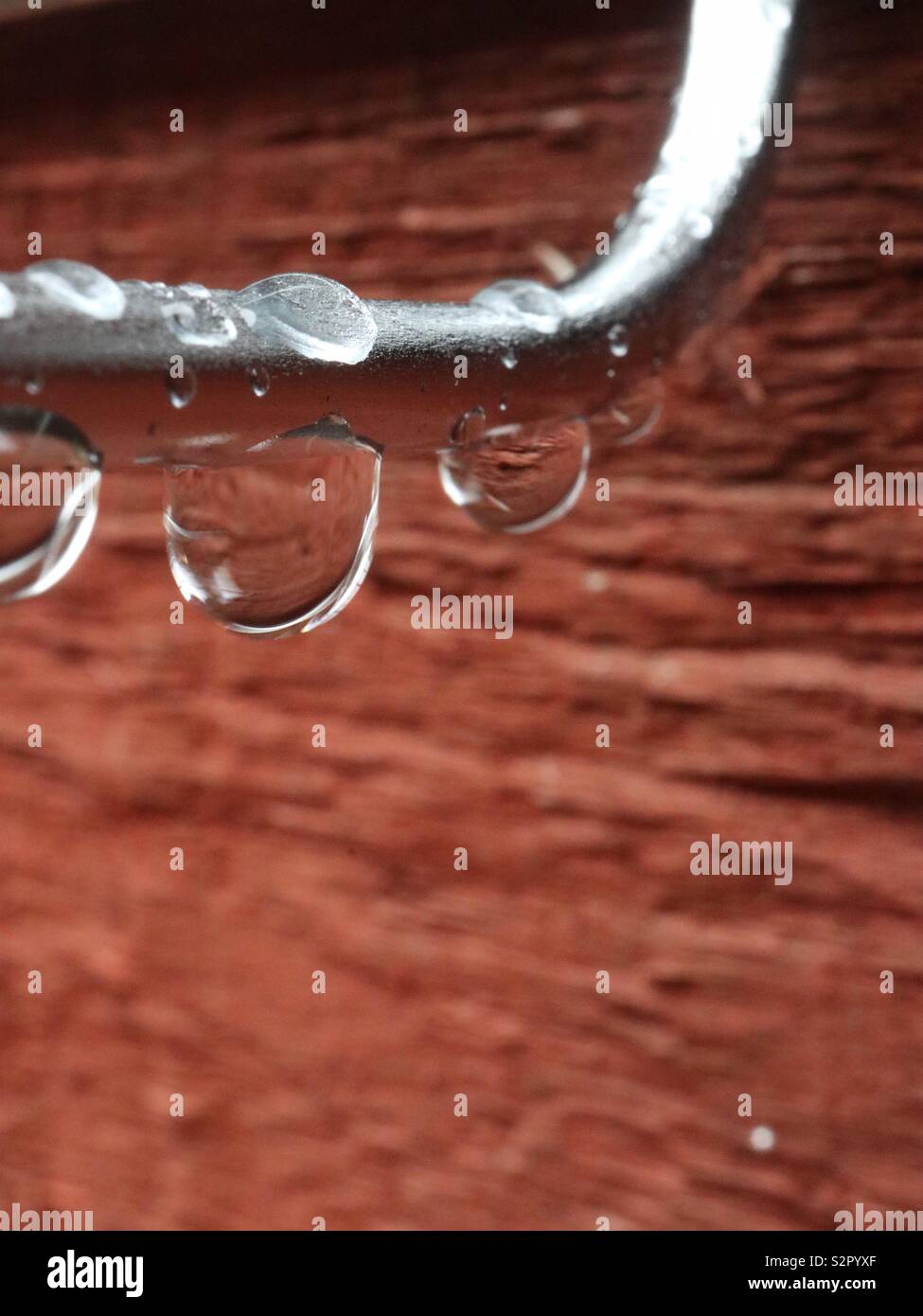 Regentropfen auf Stahl mit einem roten - Zeder Panel Stockfoto