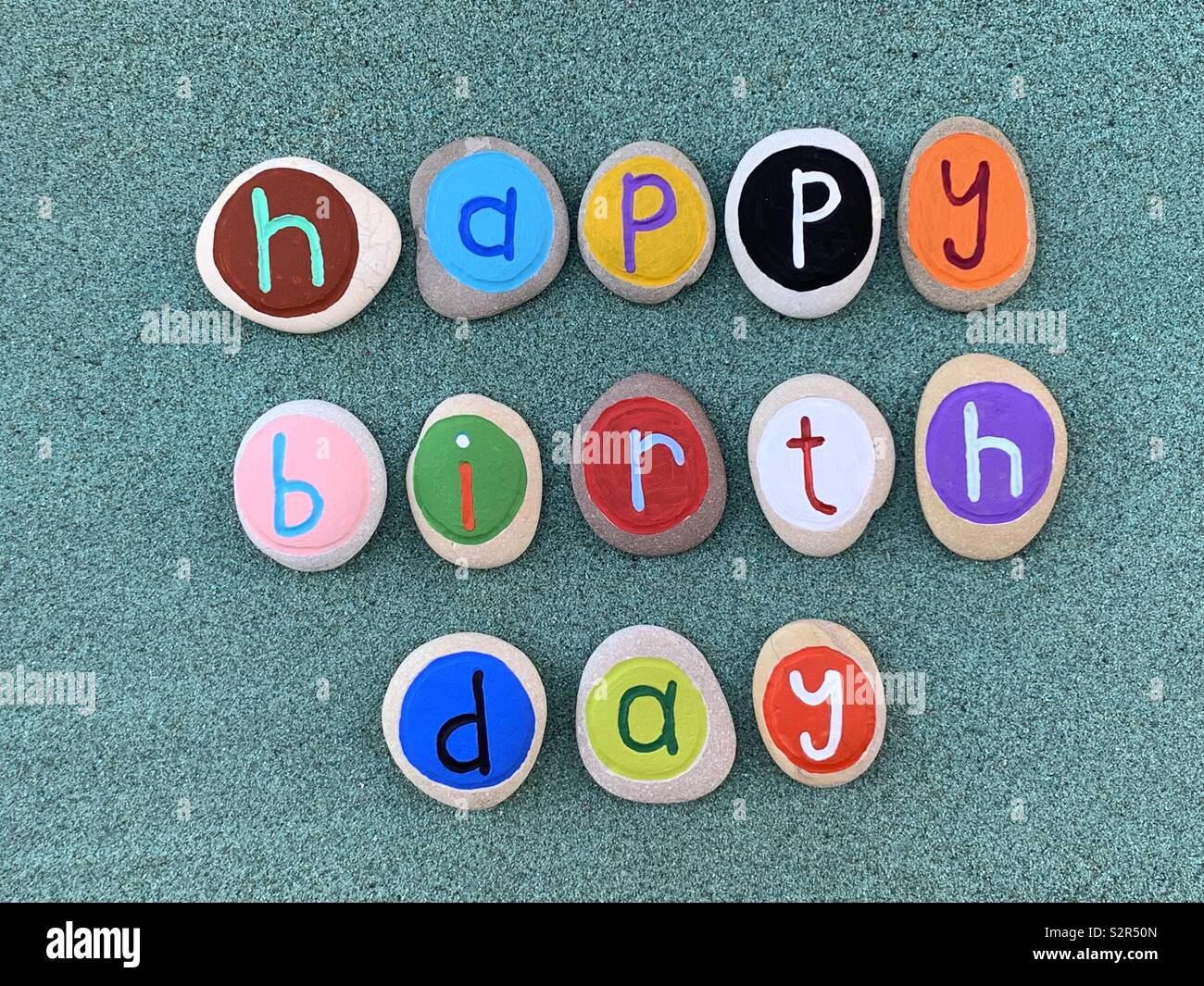Alles Gute zum Geburtstag Text mit Kreativen farbigen Stein Briefe über grünen Sand Stockfoto