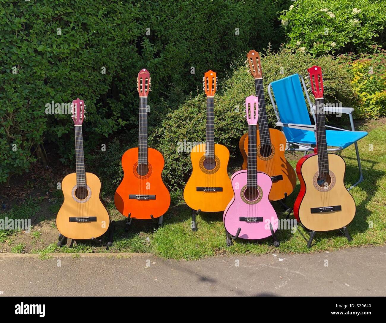 Sechs akustische Gitarren und ein Klappstuhl - Smartphone-aufgenommenes Stockfoto