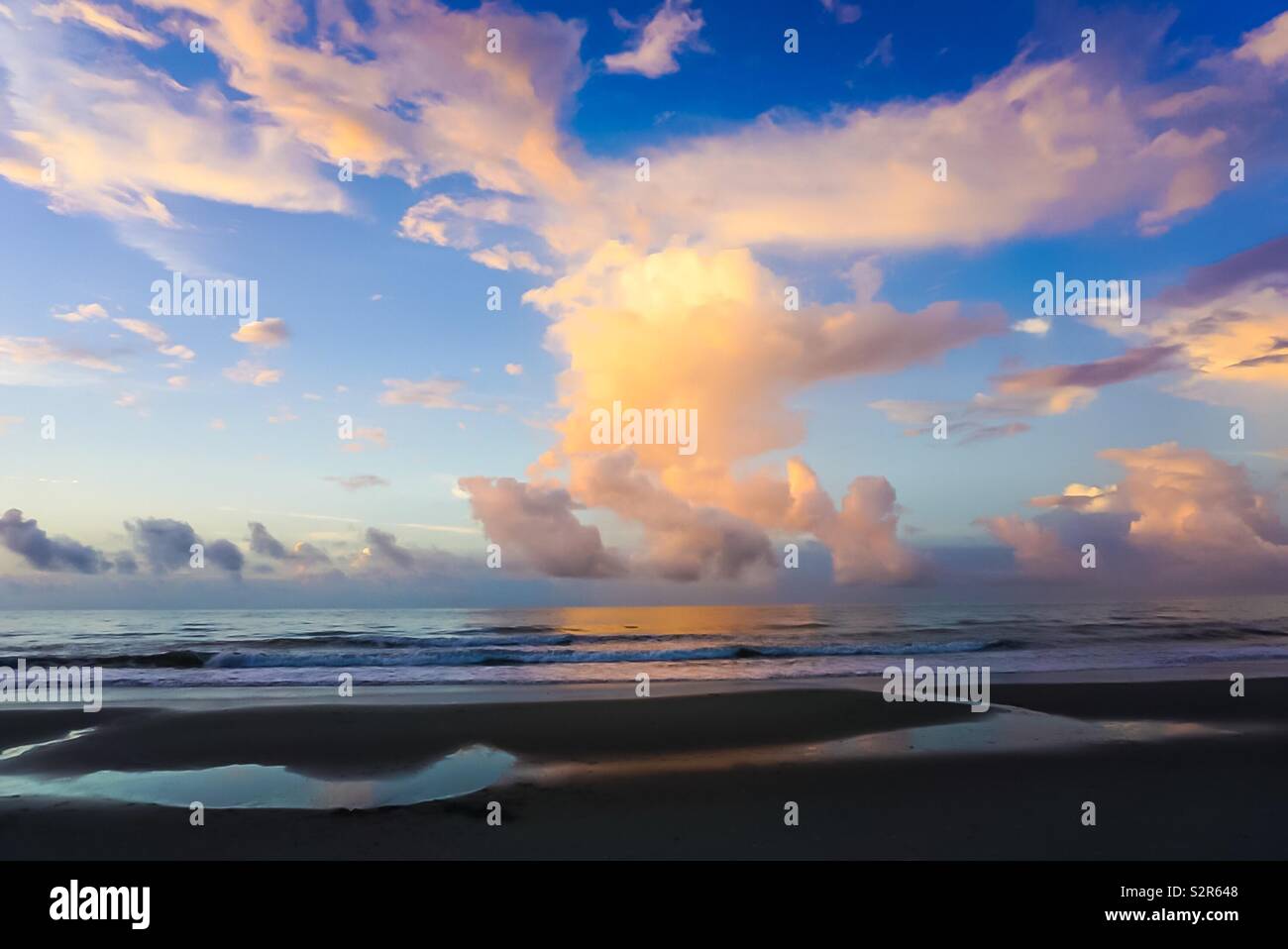 Ein bunter Sonnenaufgang über dem Wasser und Strand Küste. Stockfoto