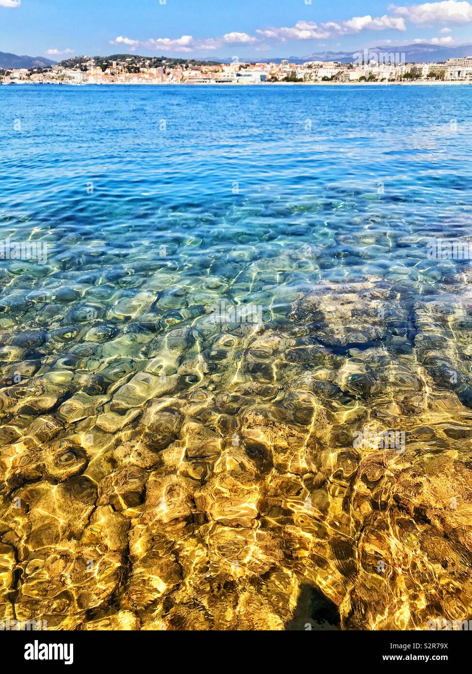 Felsen unter Wasser im Morgenlicht mit sanften Wellen auf der Oberfläche des Meeres - Smartphone-aufgenommenes Stockfoto