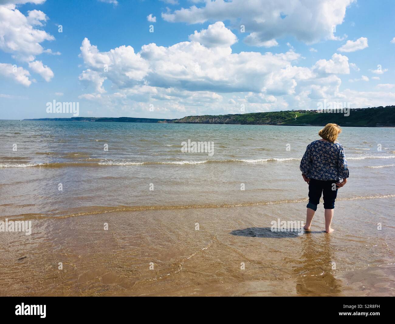 Frau Paddeln im Meer an der Küstenstadt Scarborough, Yorkshire, Vereinigtes Königreich Stockfoto